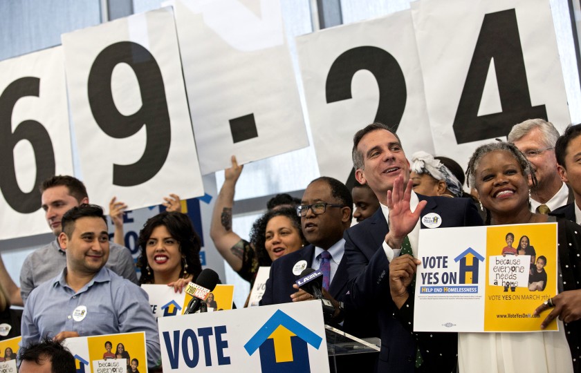 L.A. County Supervisor Mark Ridley-Thomas, center, and Los Angeles Mayor Eric Garcetti, are seen celebrating the passage of Measure H in 2017. (Brian van der Brug / Los Angeles Times)