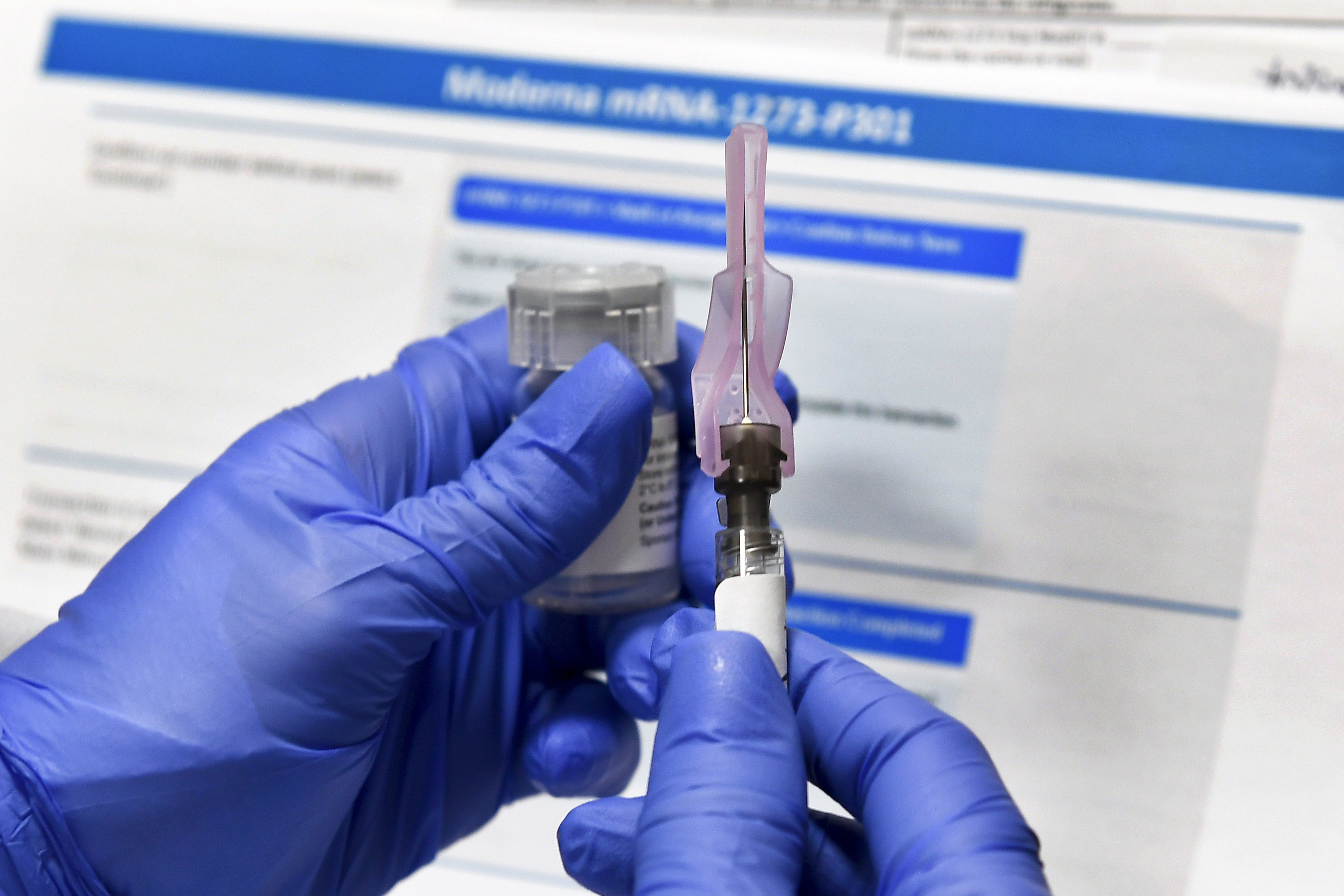 In this July 27, 2020 file photo, a nurse prepares a shot as a study of a possible COVID-19 vaccine, developed by the National Institutes of Health and Moderna Inc., gets underway in Binghamton, N.Y. Who gets to be first in line for a COVID-19 vaccine? U.S. health authorities hope by late next month to have some draft guidance on how to ration initial doses, but it’s a vexing decision. (AP Photo/Hans Pennink)