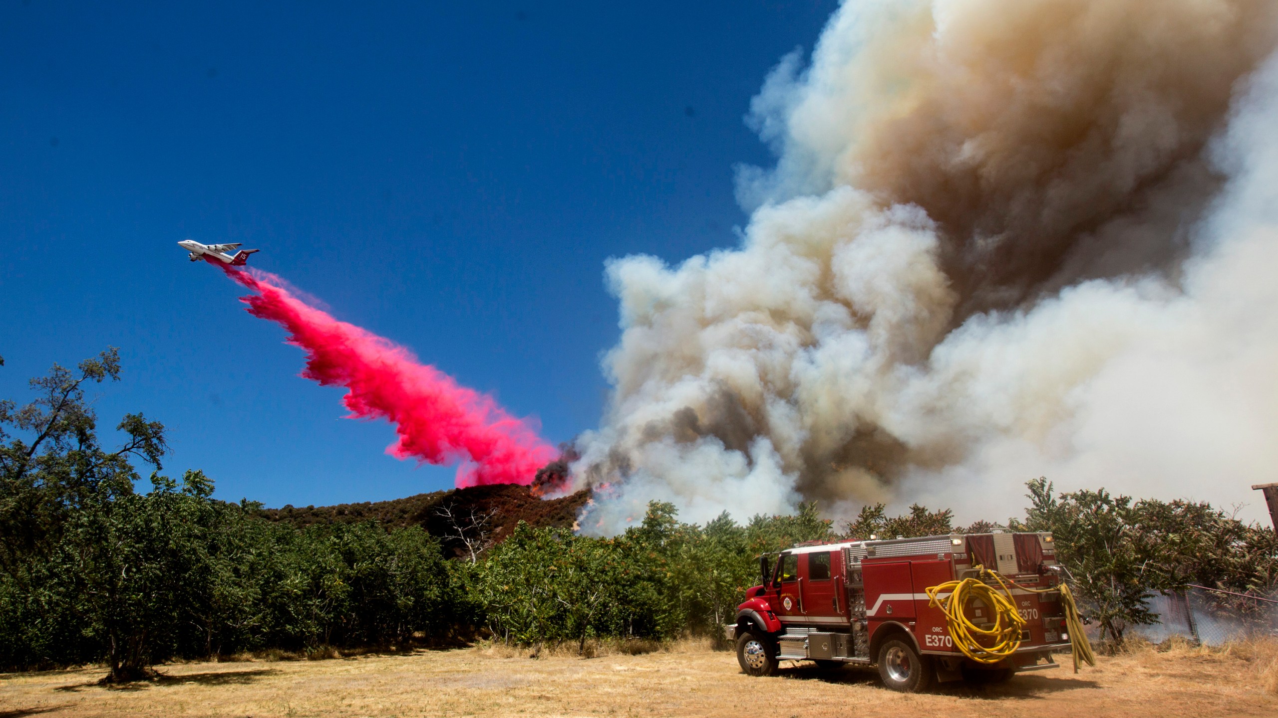 An air tanker drops fire retardant to a brush fire at the Apple Fire in Cherry Valley, Calif., Saturday, Aug. 1, 2020. (AP Photo/Ringo H.W. Chiu)