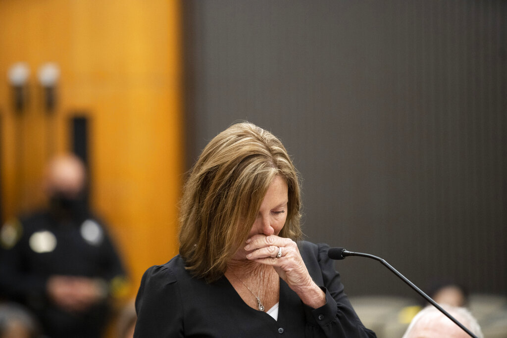 Kris Pedretti reads a statement at the podium as Joseph James DeAngelo is in the court room during the first day of victim impact statements at the Gordon D. Schaber Sacramento County Courthouse on Tuesday, Aug. 18, 2020, in Sacramento, Calif. Pedretti was 15 years old when DeAngelo broke into her Carmichael, Calif., home and raped her. The scope of his crimes "is simply staggering,” prosecutors said in a court summary released Monday — 13 known murders and nearly 50 rapes between 1975 and 1986. (Santiago Mejia/San Francisco Chronicle via AP, Pool)