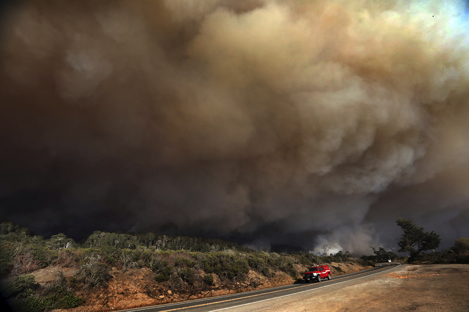 A massive column of smoke rises above Highway 1 just north of the Santa Cruz County line as a section of the CZU August Lightning Complex burns above Waddell Beach, Wednesday Aug. 19, 2020, northwest of Santa Cruz, Calif. (Shmuel Thaler/The Santa Cruz Sentinel via AP)