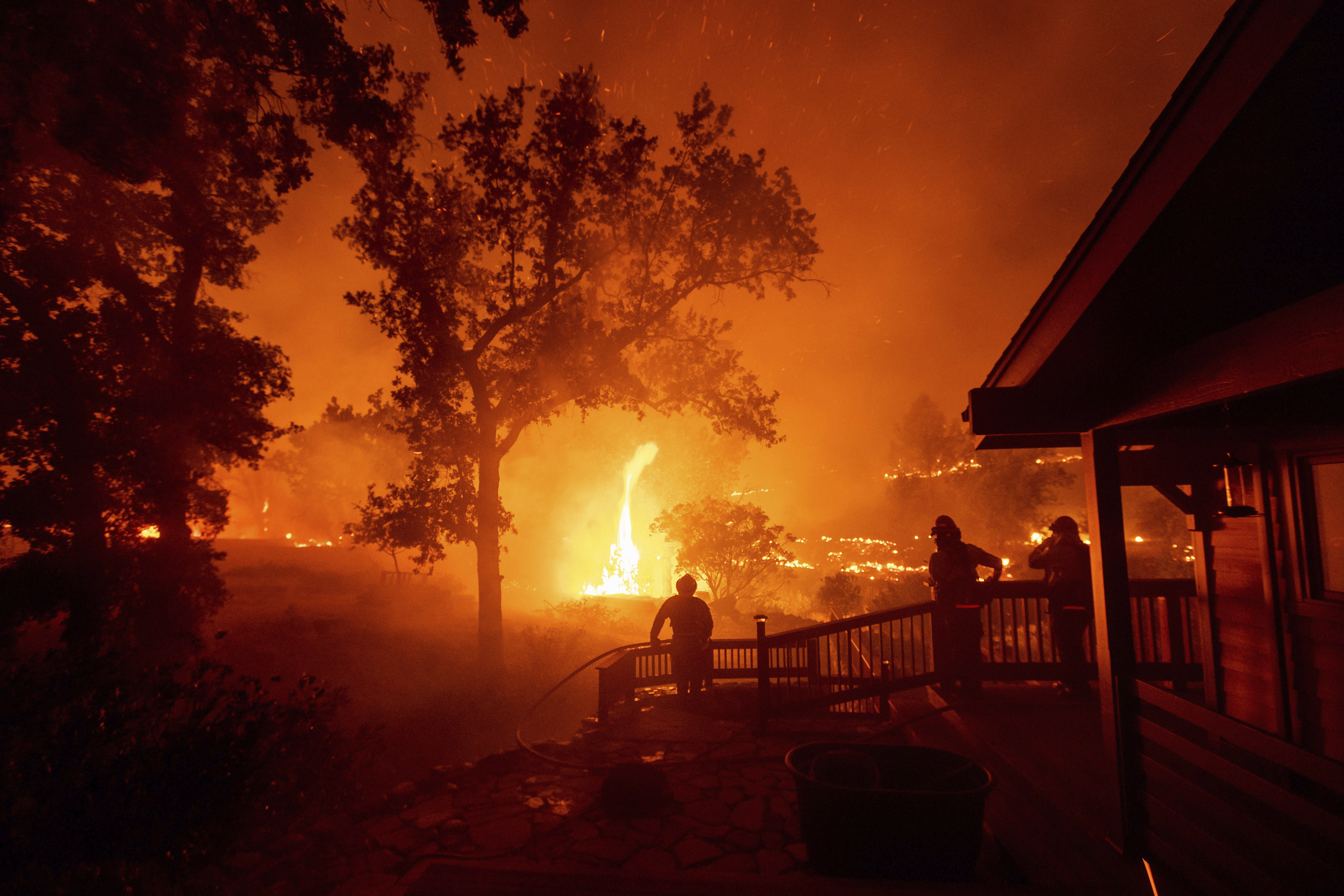 Firefighters watch flames from the LNU Lightning Complex fires approach a home in the Berryessa Estates neighborhood of unincorporated Napa County on Aug. 21, 2020. (AP Photo/Noah Berger)