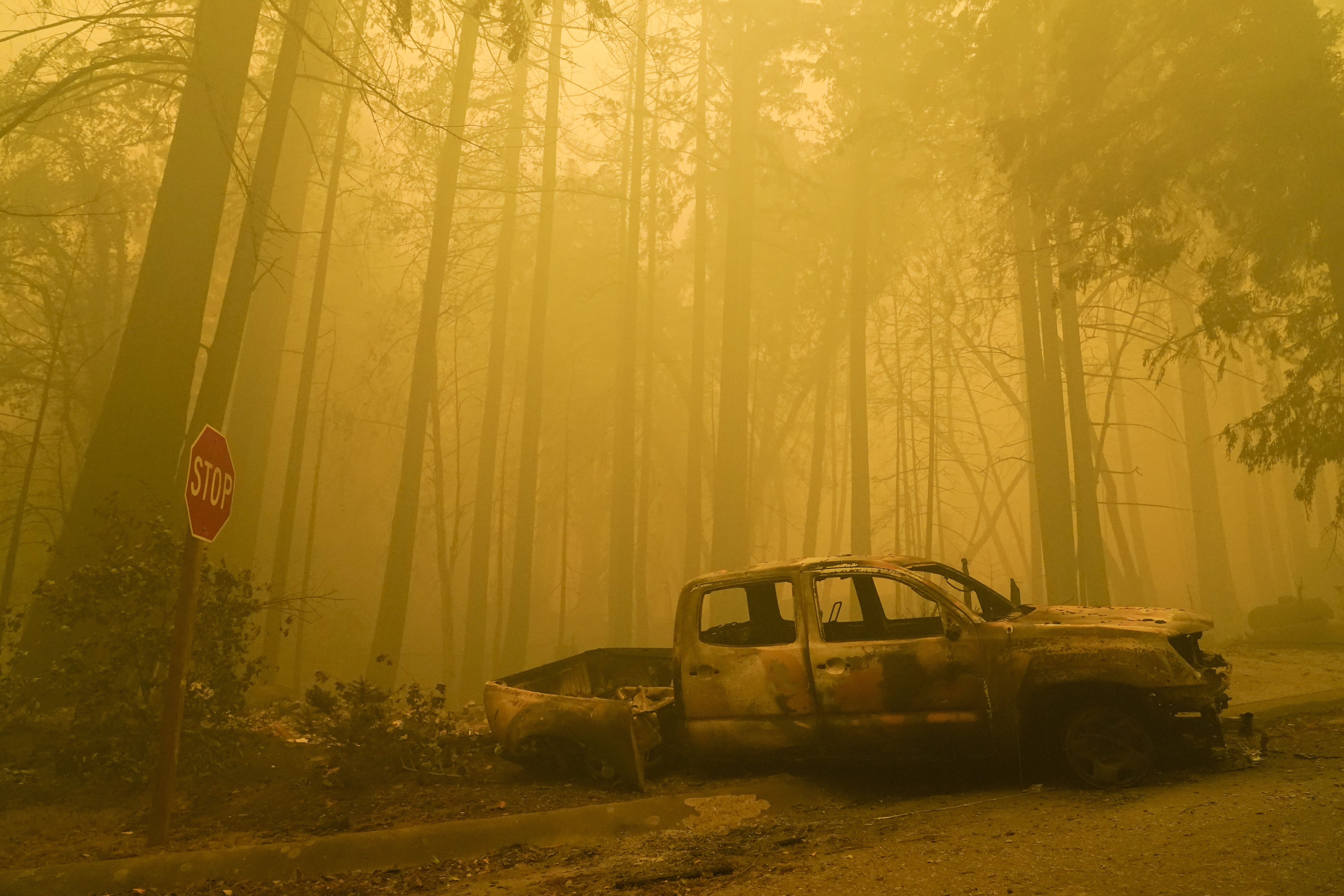 A burned out vehicle is left in front of a fire- ravaged residence as smoke from the CZU August Lightning Complex Fire fills the sky Aug. 22, 2020, in Boulder Creek, Calif. (AP Photo/Marcio Jose Sanchez)