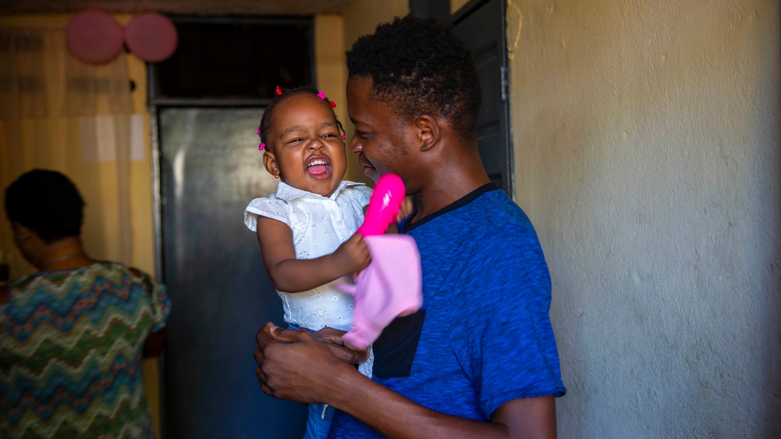 Verty holds up his 1-year-old daughter at his house in Port-au-Prince, Haiti, Tuesday, Aug. 25, 2020. The Trump administration has sharply increased its use of hotels to detain immigrant children before expelling them from the United States during the coronavirus pandemic. Verty says government contractors at a hotel where he was detained gave his family, including his daughter, cups of ice to eat to pass temperature checks prior to their deportation flight, even though they had tested negative for COVID-19. (AP Photo/Dieu Nalio Chery)