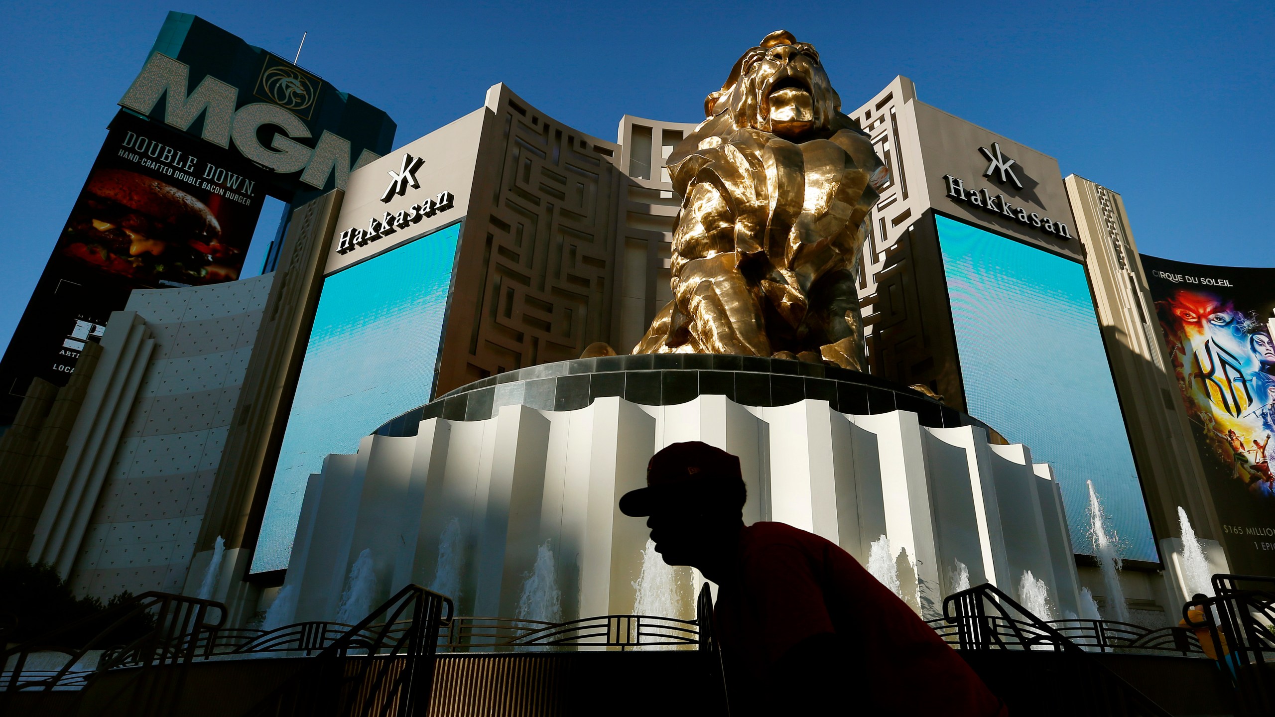 In this Aug. 3, 2015, file photo, a man rides his bike past the MGM Grand hotel and casino in Las Vegas. MGM Resorts plans to lay off 18,000 workers as the casino company struggles with the fallout from the pandemic. The Las Vegas-based parent of the Bellagio said in a letter to employees that furloughed employees will keep health benefits until Sept. 30, 2020 according to a report in The Wall Street Journal. (AP Photo/John Locher, File)