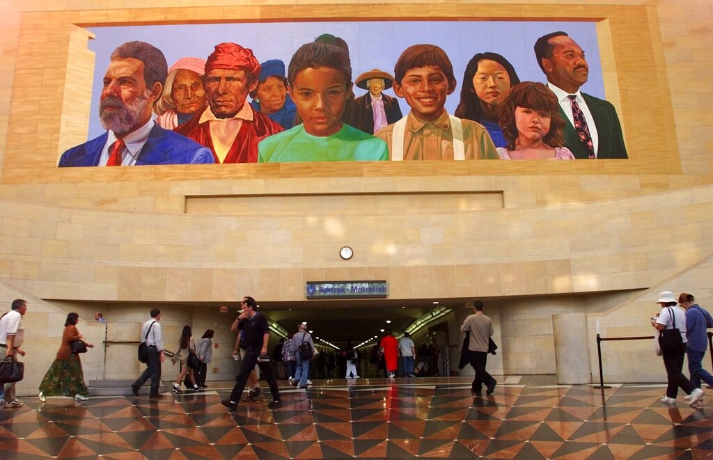 In this Aug. 30, 2000, file photo, commuters walk into a tunnel at Union Station under the mural "City of Dreams/River of History" by artist Richard Wyatt, showing the diversity of California's population. (AP Photo/Damian Dovarganes, File)