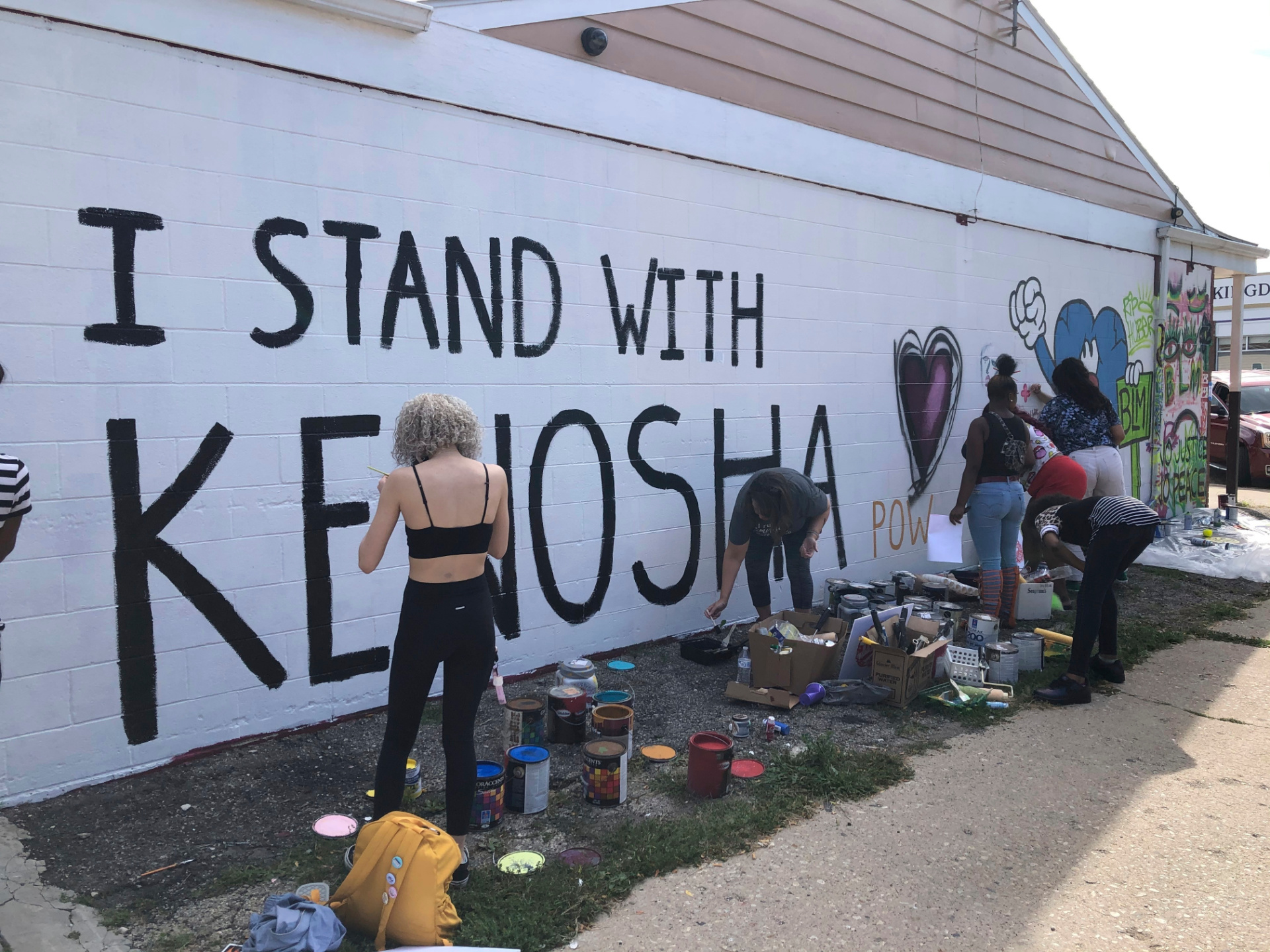 Volunteers paint murals on boarded-up businesses in Kenosha, Wis., on Sunday, Aug. 30, 2020, at an "Uptown Revival." The event was meant to gather donations for Kenosha residents and help businesses hurt by violent protests that sparked fires across the city following the police shooting of Jacob Blake. (AP Photo/ Russell Contreras)