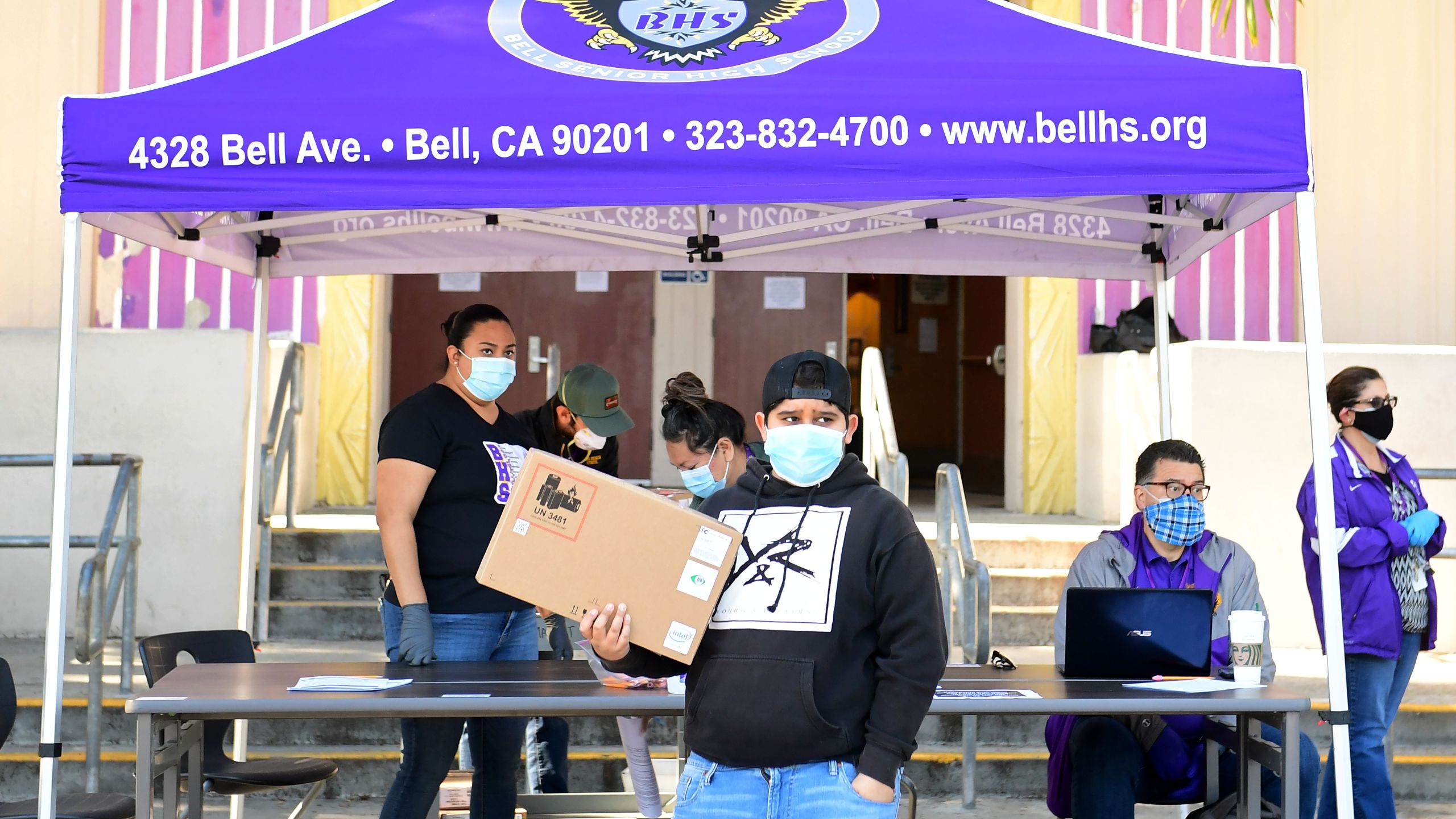 A student receives his laptop computer for remote learning which will be returned after the school year is over in front of Bell High School in Bell, California on April 15, 2020. (FREDERIC J. BROWN/AFP via Getty Images)