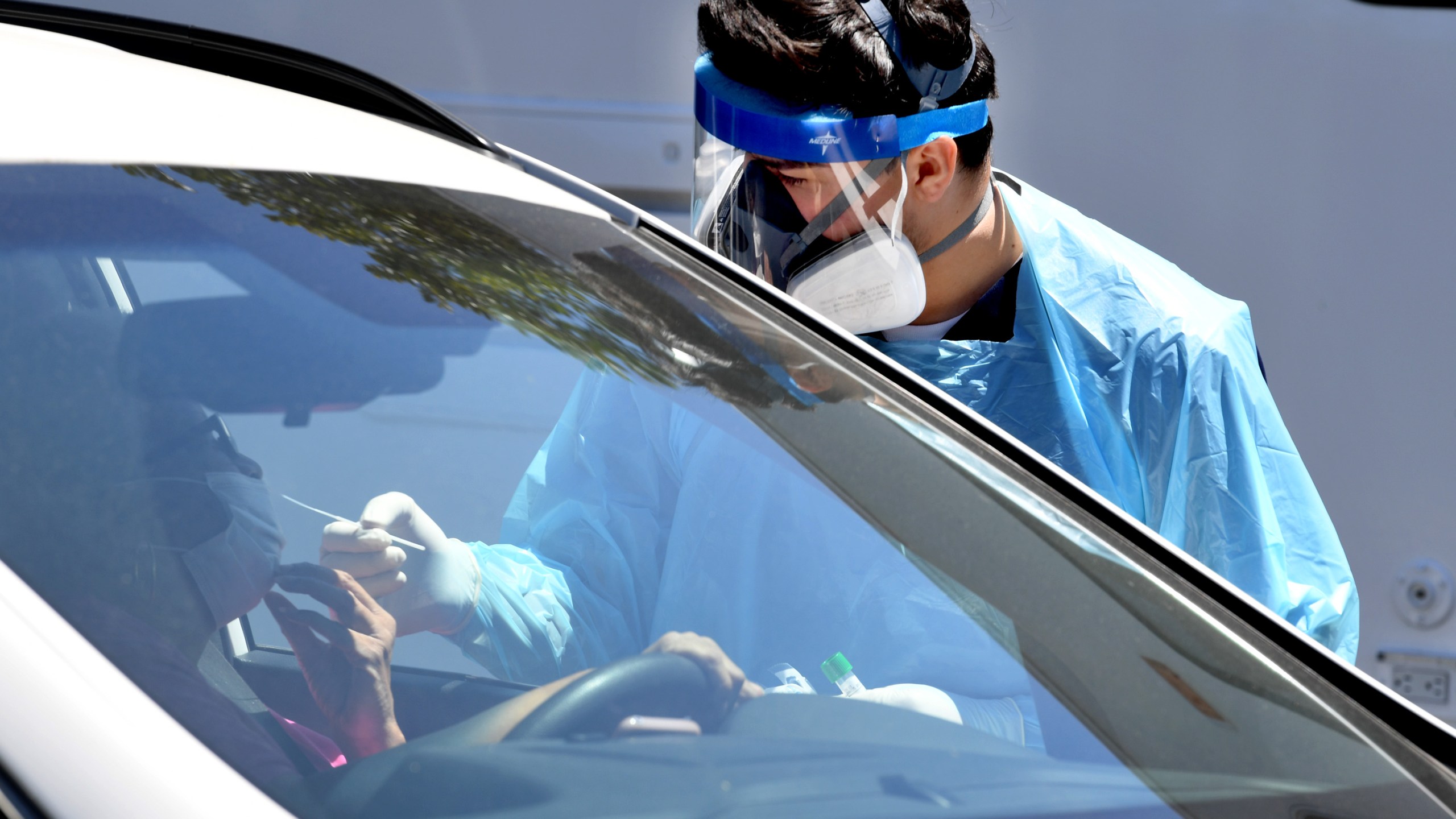 Workers wearing personal protective equipment (PPE) perform drive-up COVID-19 testing administered from a car at Mend Urgent Care testing site for the novel coronavirus at the Westfield Culver City on April 24, 2020 in the Culver City neighborhood of Los Angeles, California. (Kevin Winter/Getty Images)