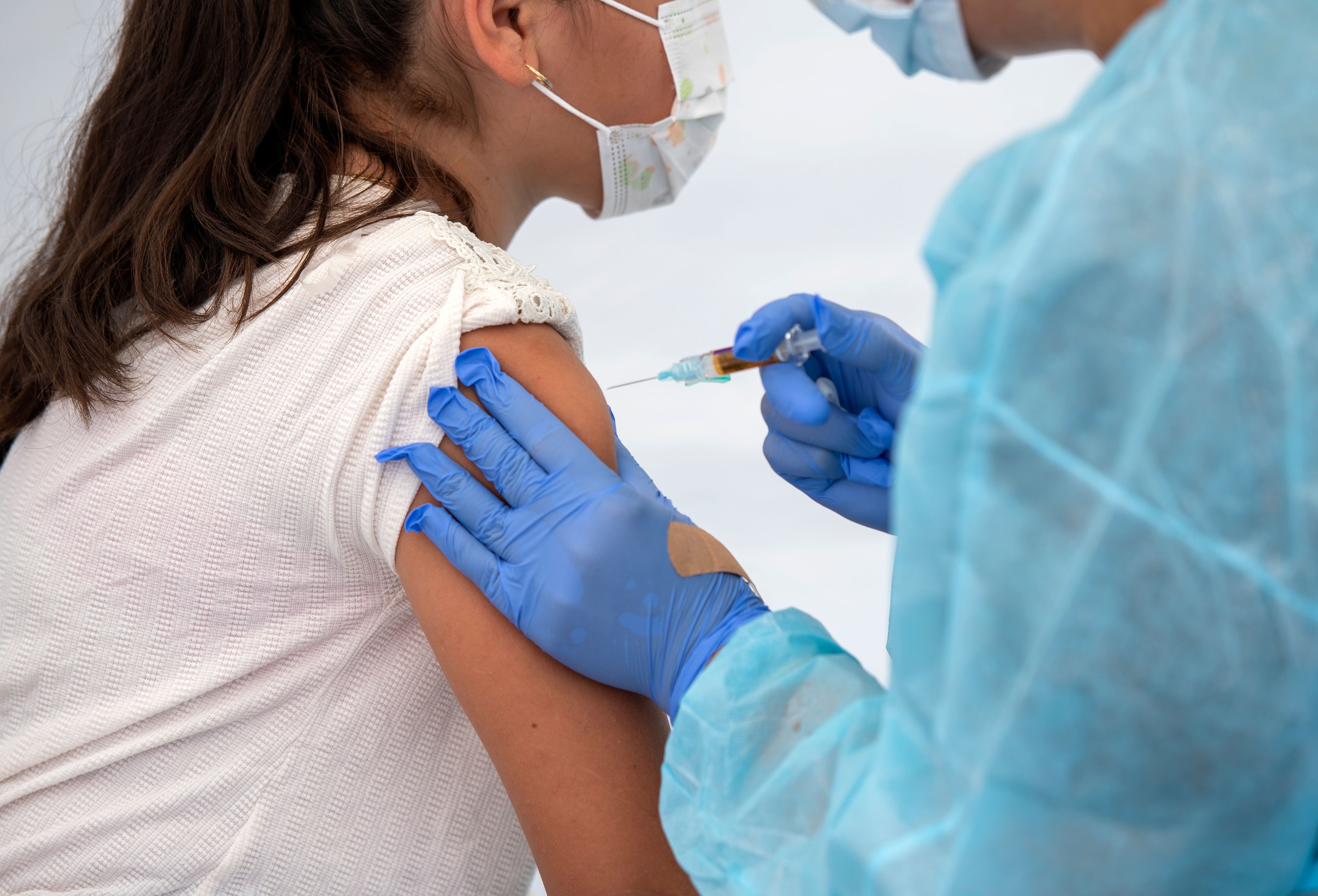 A health worker vaccinates a child during the Saban Community Clinic Vaccine Drive Up for L.A. Children on Aug.12, 2020, in Los Angeles. (VALERIE MACON/AFP via Getty Images)