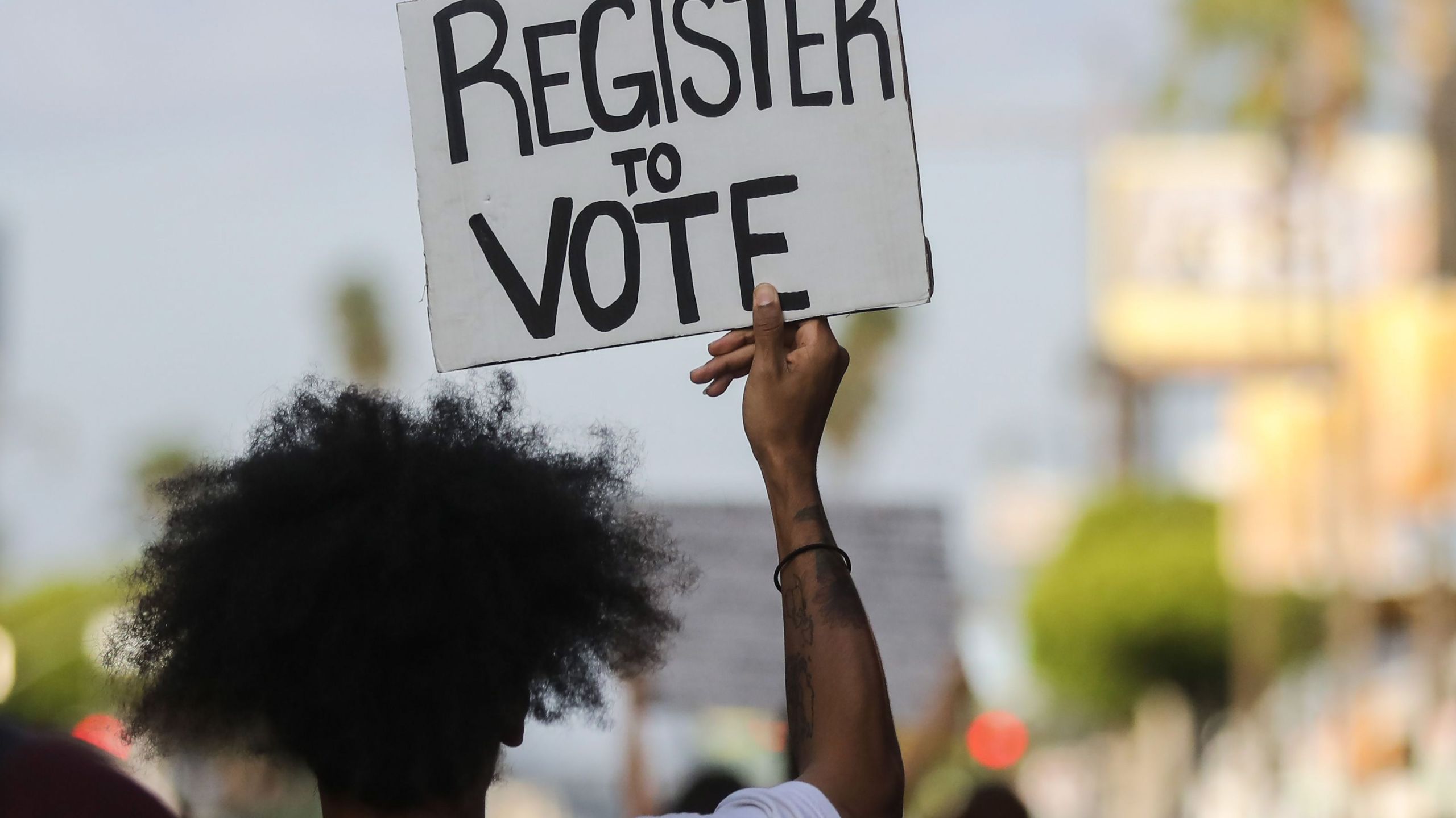 A protester carries a 'Register to Vote' sign during a peaceful demonstration against racism and police brutality on June 6, 2020 in Los Angeles. (Mario Tama/Getty Images)