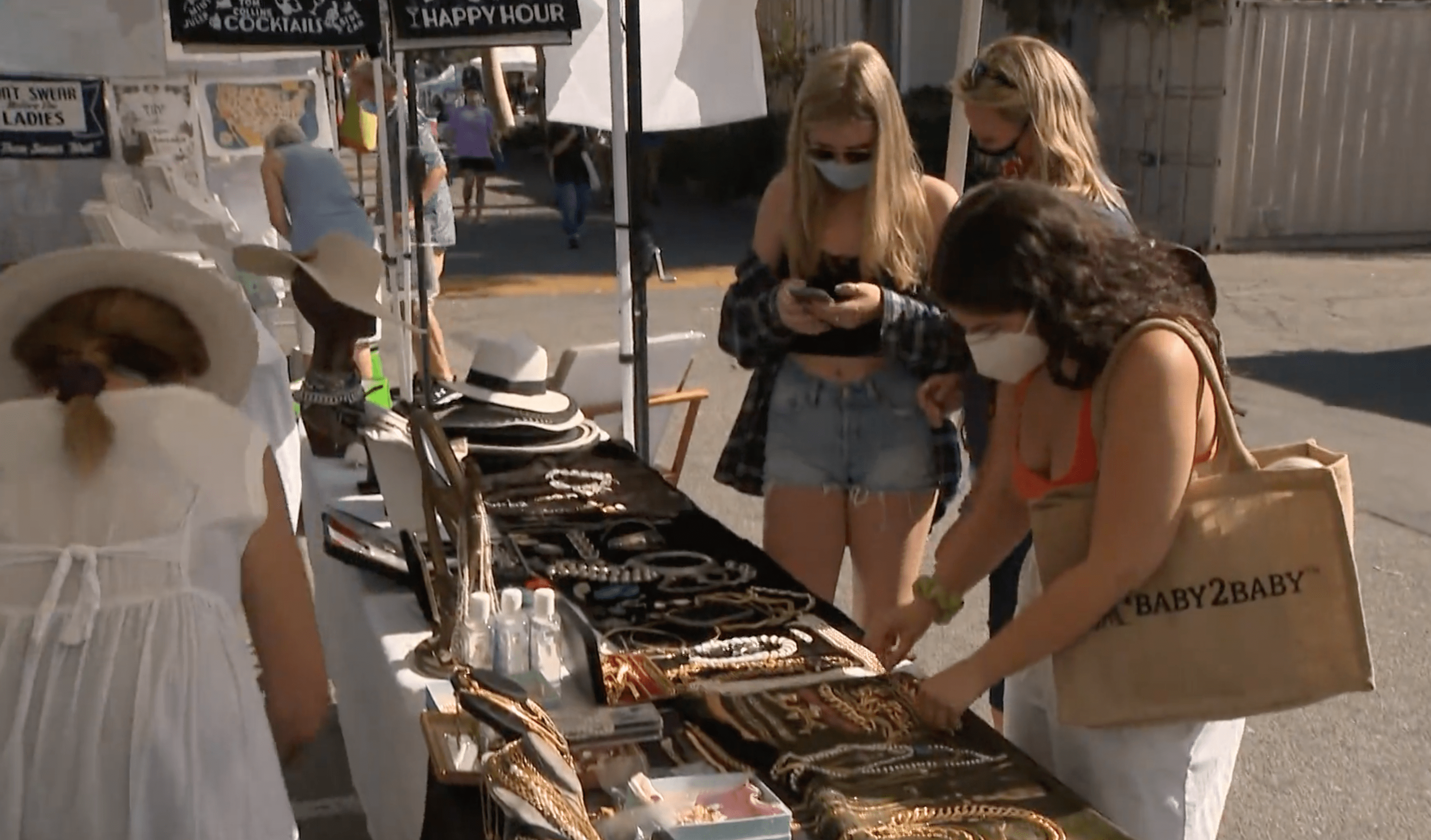 Women in face masks look at jewelry at the Melrose Trading Post flea market in Fairfax on Aug. 2, 2020. (KTLA)