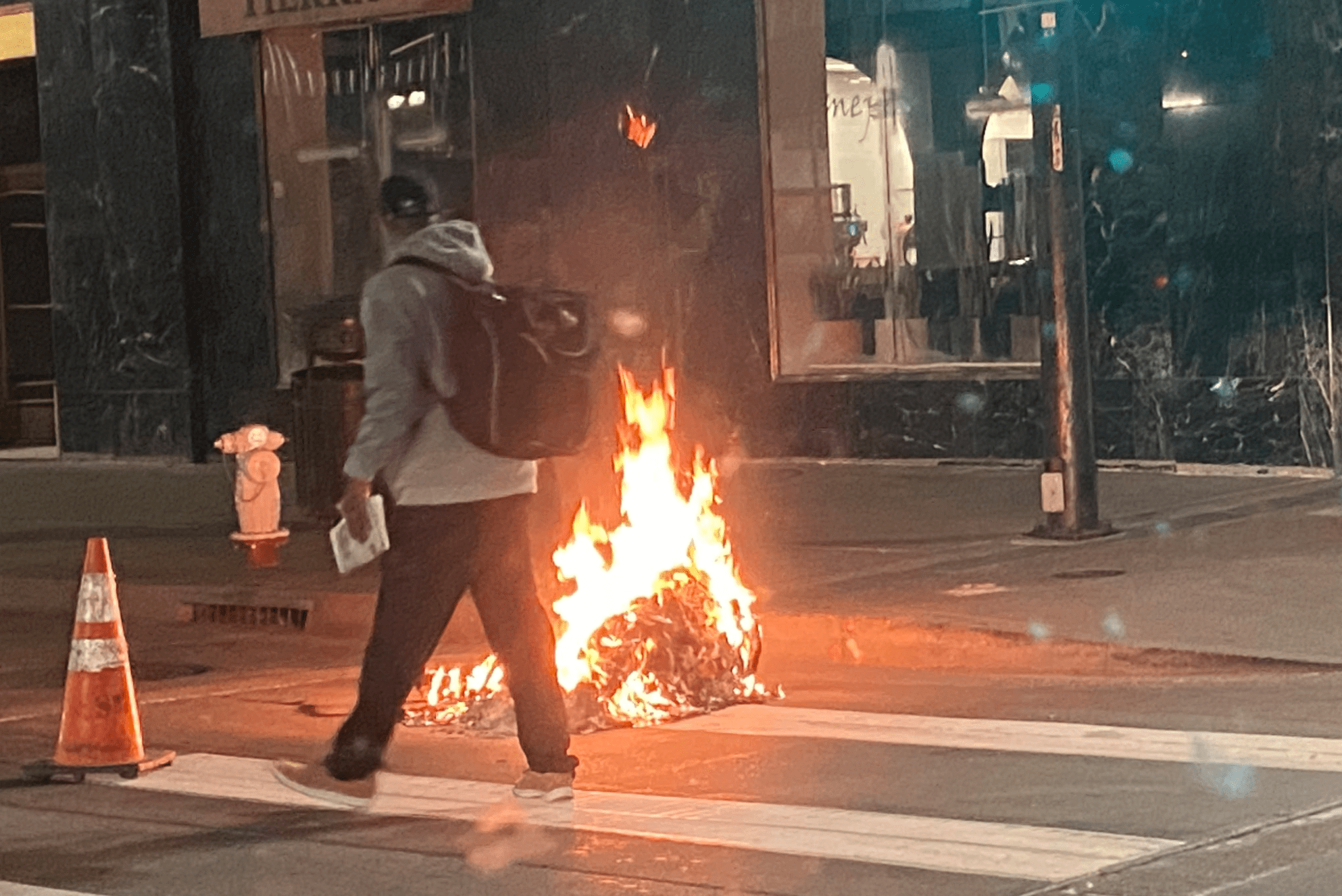 A man is seen by a fire burning in an Oakland street on Aug. 26, 2020. (Oakland Police Department)