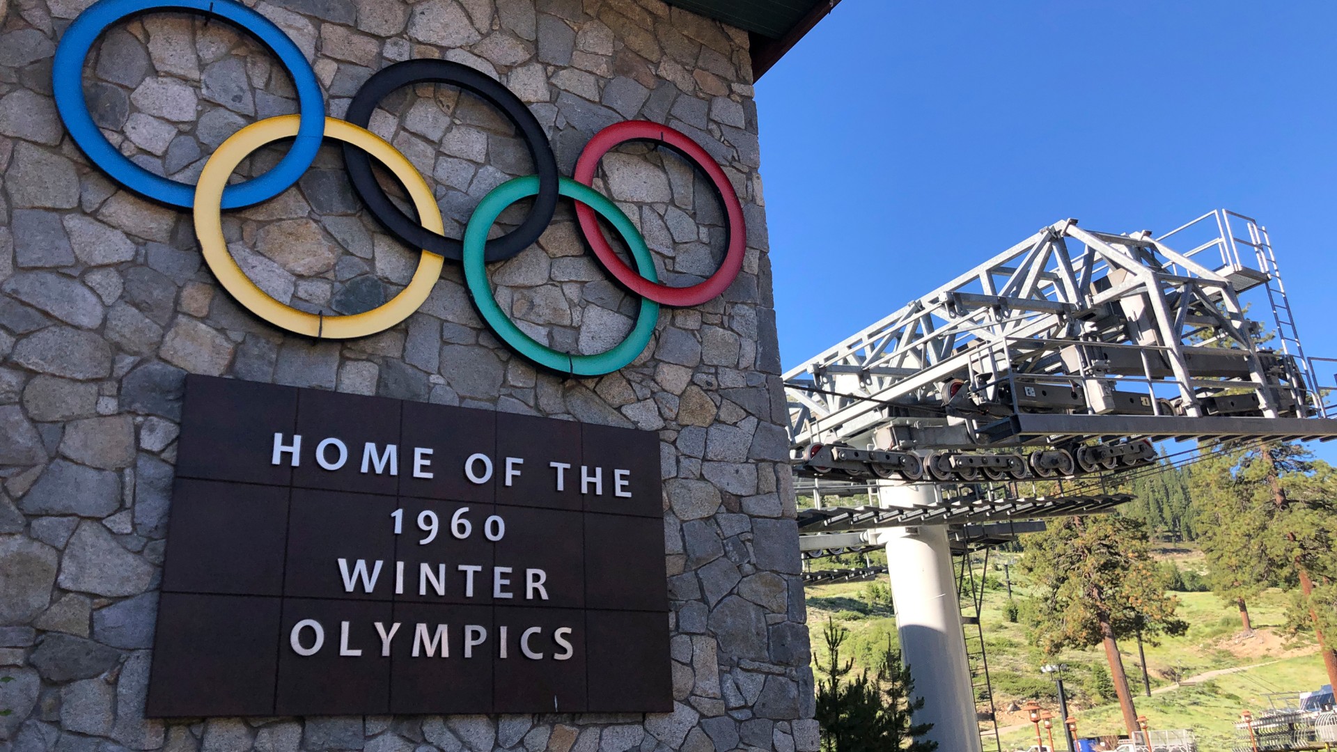 A sign marking the 1960 Winter Olympics is seen by a chairlift at Squaw Valley Ski Resort in Olympic Valley, Calif., July 9, 2020. California's Squaw Valley Ski Resort is considering changing its name to remove "squaw," a derogatory term for Native American women. Squaw Valley President & CEO Ron Cohen says resort officials are meeting with shareholders and the local Washoe tribal leadership to get their input. He says he can't give a timeline on when the decision will be made. The renaming of Squaw Valley Ski Resort is one of many efforts across the nation to address colonialism and indigenous oppression. (AP Photo/Haven Daley)