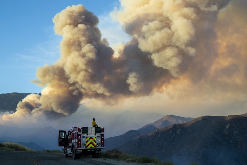 A firefighter from Carpinteria monitors a huge plume of smoke from the Apple north of Banning in this undated photo. (Gina Ferazzi / Los Angeles Times)