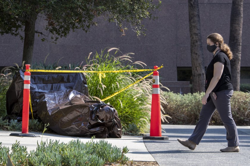 A vandalized statue is wrapped in a brown tarp in Grand Park on Aug. 14, 2020. (Brian van der Brug/Los Angeles Times)