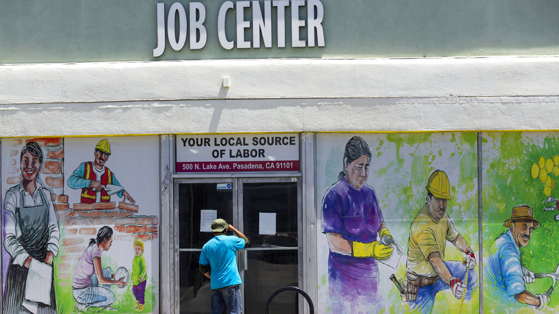 FILE - In this May 7, 2020, file photo, a person looks inside the closed doors of the Pasadena Community Job Center in Pasadena, Calif., during the coronavirus outbreak. (AP Photo/Damian Dovarganes, File)