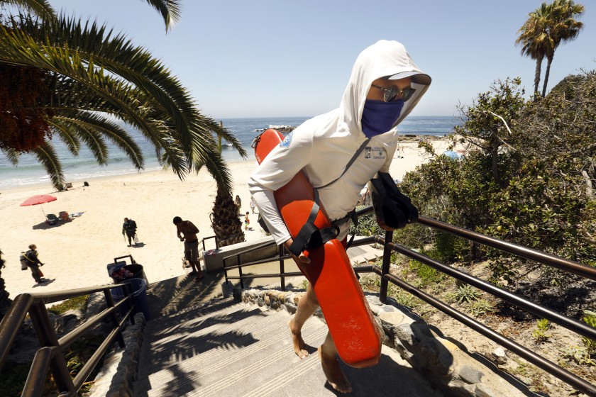 A lifeguard wearing a face covering heads up the steps at Heisler Park in Laguna Beach in this undated photo.(Carolyn Cole / Los Angeles Times)