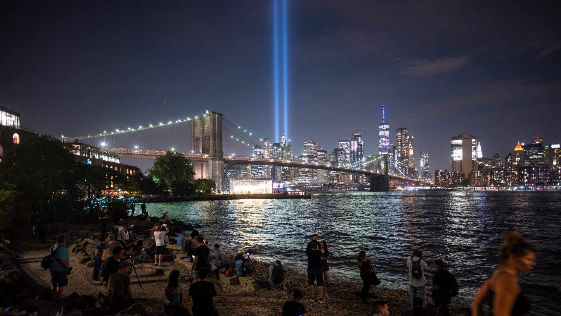 People on the shore watch The Tribute in Light shining into the sky over Manhattan's skyline on September 11, 2019 in New York. (JOHANNES EISELE/AFP via Getty Images)