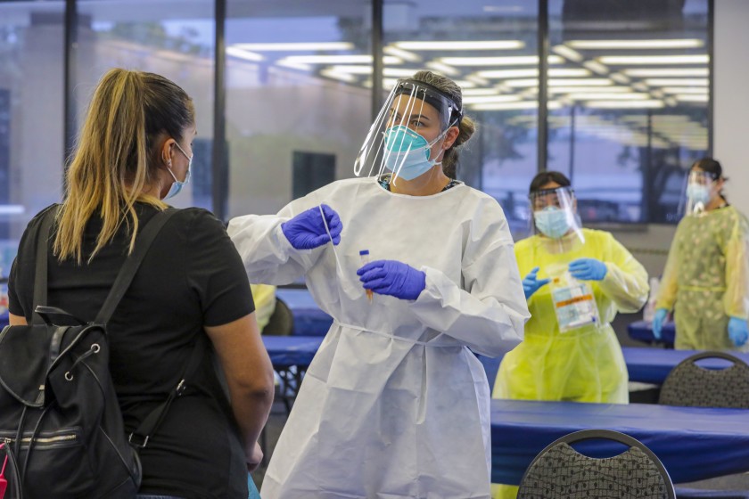 Elizabeth McKinnon explains to Glenda Guerra how to self-swab for a COVID-19 test at the Ontario Convention Center on July 24, 2020. (Irfan Khan / Los Angeles Times)