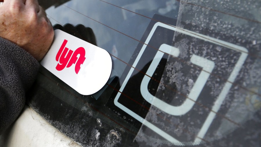 In this Jan. 31, 2018, file photo, a Lyft logo is installed on a Lyft driver's car next to an Uber sticker in Pittsburgh. (AP Photo/Gene J. Puskar, File)