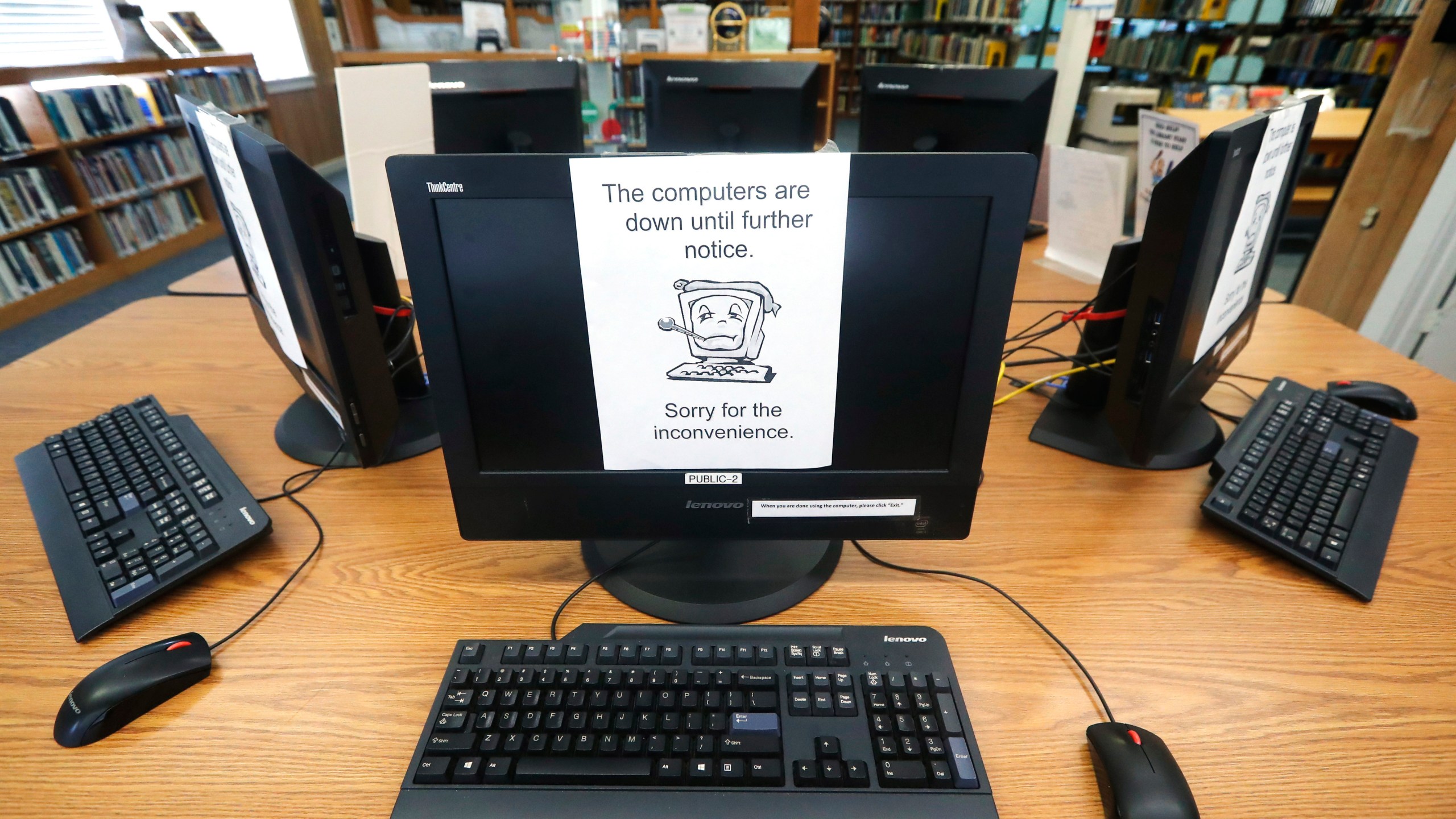 In this Aug. 22, 2019, file photo, signs on a bank of computers tell visitors that the machines are not working at the public library in Wilmer, Texas. (AP Photo/Tony Gutierrez, File)