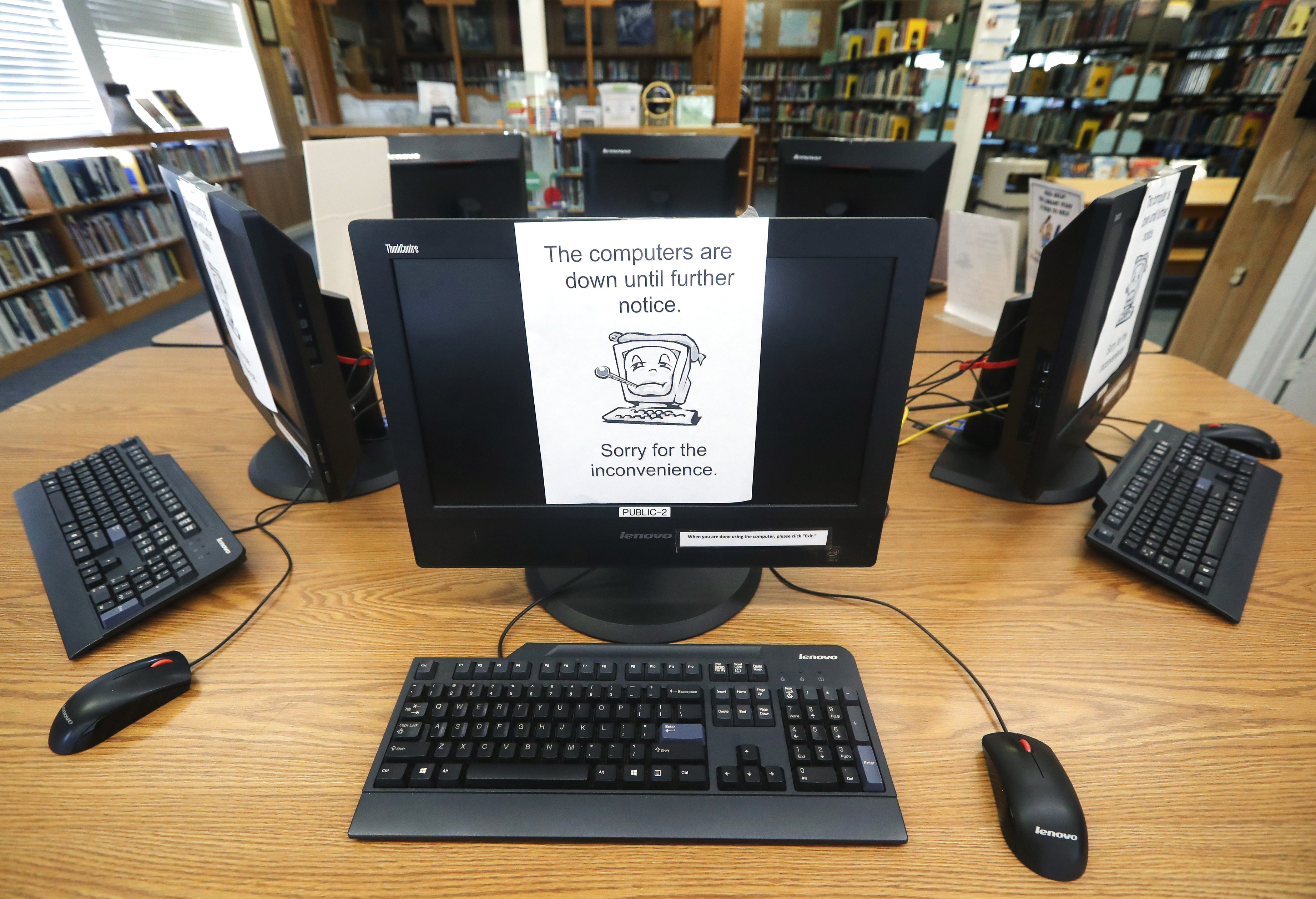 In this Aug. 22, 2019, file photo, signs on a bank of computers tell visitors that the machines are not working at the public library in Wilmer, Texas. (AP Photo/Tony Gutierrez, File)