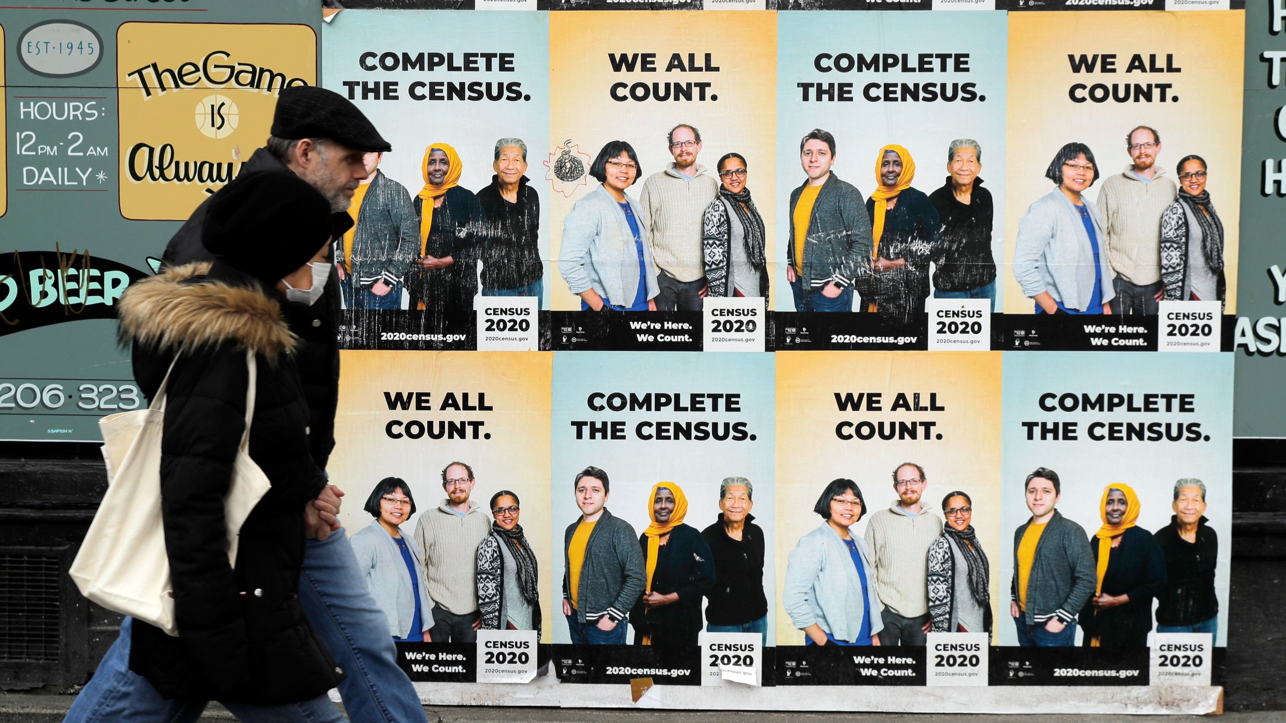 People walk past posters encouraging participation in the 2020 Census in Seattle's Capitol Hill neighborhood in this April 1, 2020, photo. (AP Photo/Ted S. Warren, File)