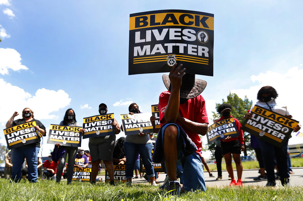 In this July 20, 2020, file photo, Eddie Perkins takes a knee during a protest rally outside Hartford Nursing & Rehabilitation Center in Detroit. (AP Photo/Paul Sancya, File)