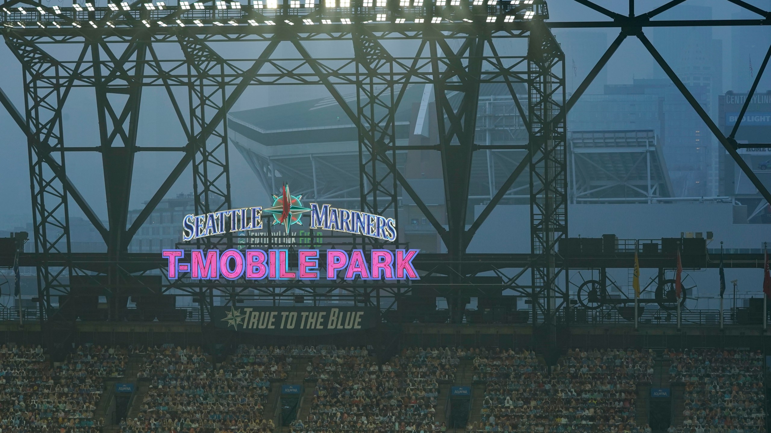 Smoke from wildfires fills the air at T-Mobile Park as photos of fans are displayed in the left field bleachers and CenturyLink Field is visible behind the ballpark sign during the second baseball game of a doubleheader between the Seattle Mariners and the Oakland Athletics, Sept. 14, 2020, in Seattle. (Ted S. Warren / Associated Press)