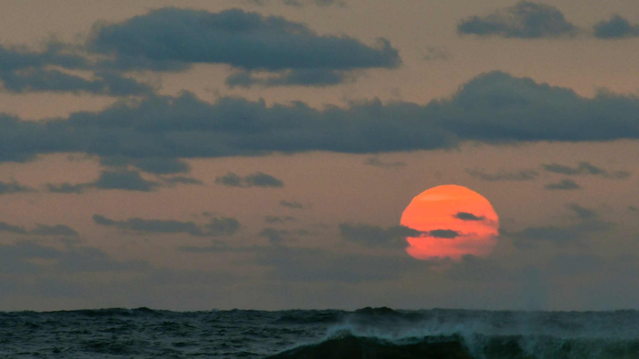 This photo taken at sunrise from Surf City on Long Beach Island in New Jersey shows the sun shrouded in smoke and brown haze Tuesday, Sept. 15, 2020. (Elizabeth Laird via AP)