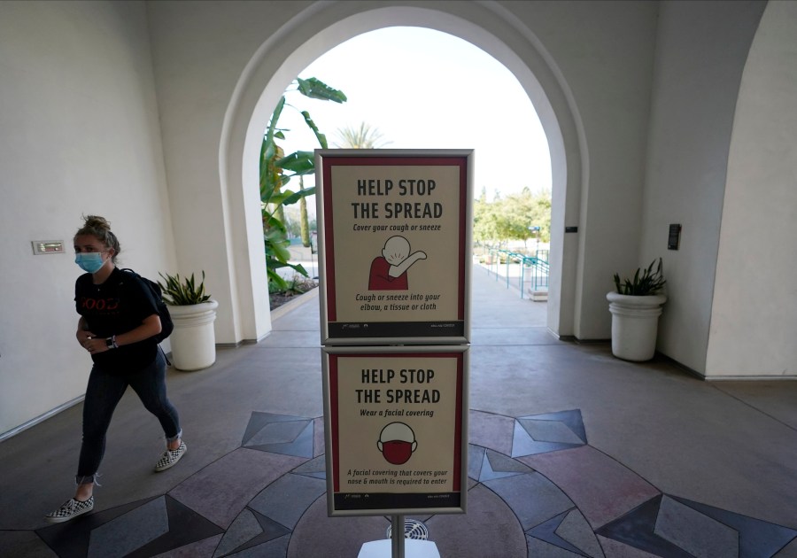 In this Sept. 2, 2020, file photo, a woman wears a mask as she walks on campus at San Diego State University in San Diego. (AP Photo/Gregory Bull, File)