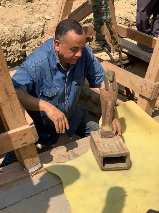 This September 2020 photo provided by the Ministry of Tourism and Antiquities shows Mostafa Waziri, secretary general of the Supreme Council of Antiquities, posing with one of more than two dozen ancient coffins unearthed near the famed Step Pyramid of Djoser in Saqqara, south of Cairo, Egypt. (Ministry of Tourism and Antiquities via AP)