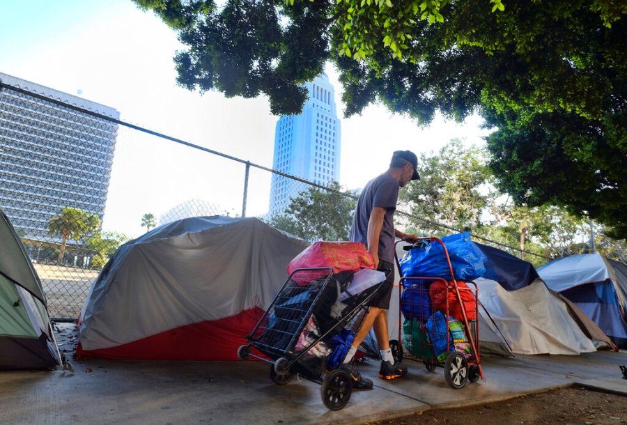 A homeless man moves his belongings from a street behind Los Angeles City Hall as crews prepared to clean the area on July 1, 2019. (Richard Vogel / Associated Press)