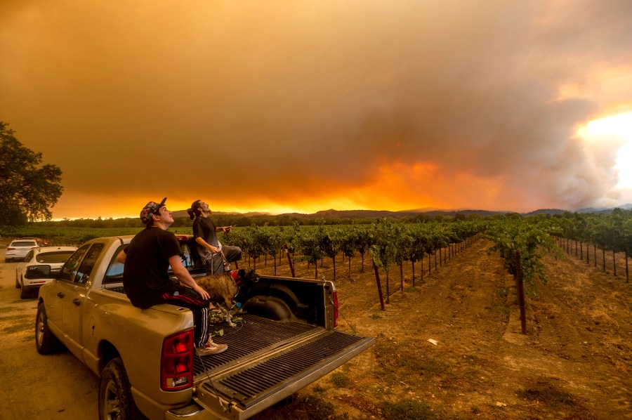 In this Aug. 20, 2020, photo, Thomas Henney, right, and Charles Chavira watch a plume spread over Healdsburg, Calif., as the LNU Lightning Complex fires burn. (AP Photo/Noah Berger, File)