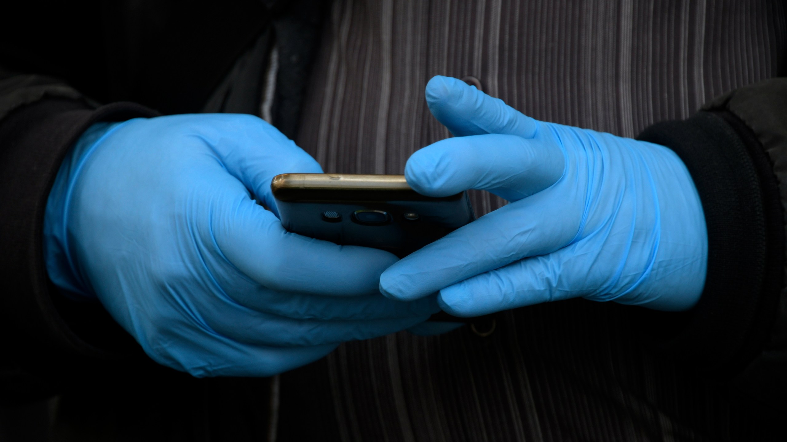 A man wearing gloves as a protective measure, holds a smartphone in Madrid on March 19, 2020. (GABRIEL BOUYS/AFP via Getty Images)