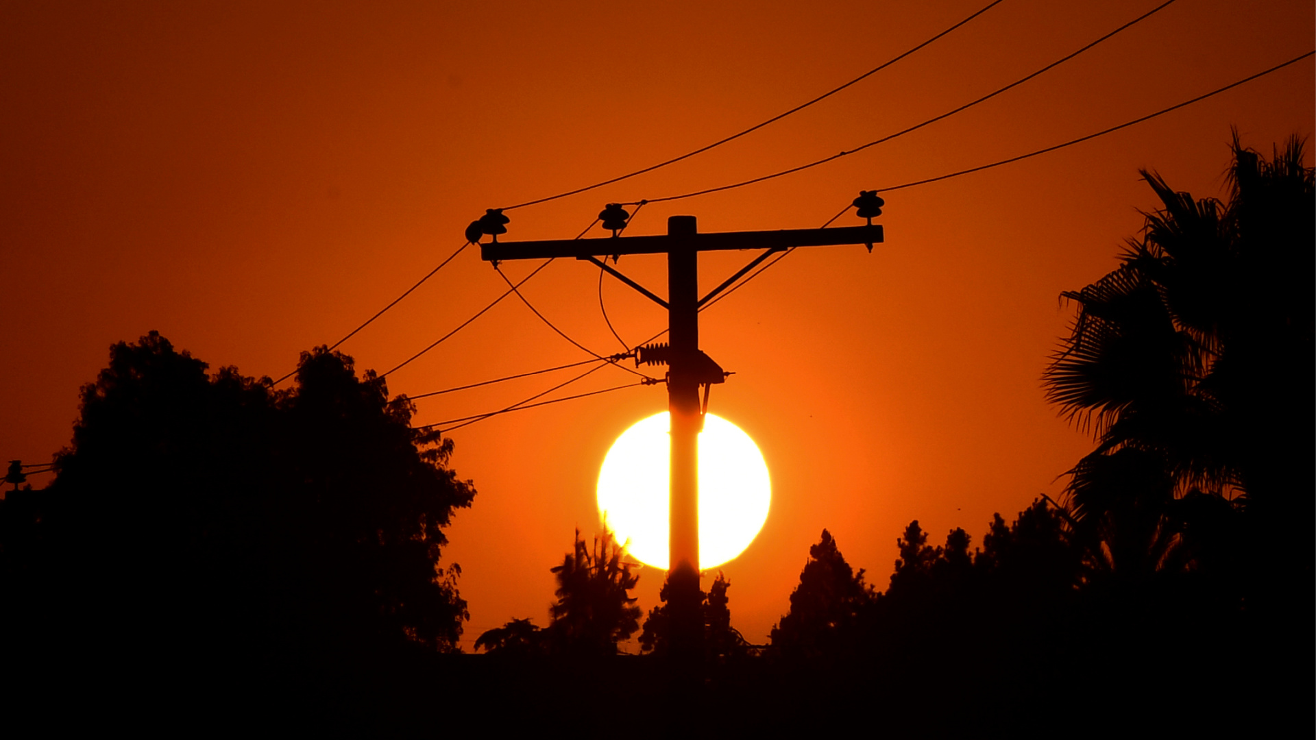 The sun sets behind power lines in Los Angeles on Sept. 3, 2020. (FREDERIC J. BROWN/AFP via Getty Images)