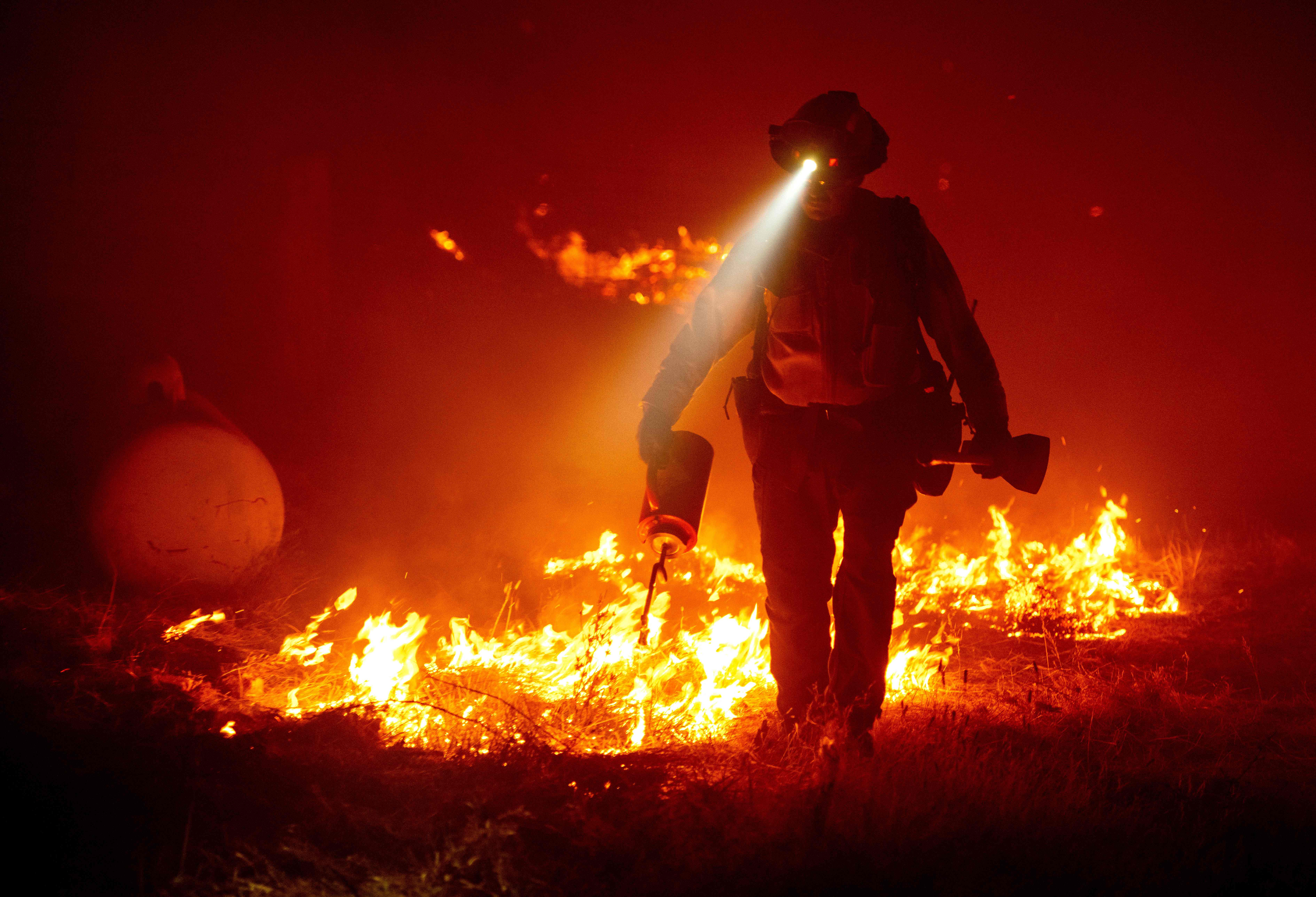 Firefighters cut defensive lines and light backfires to protect structures behind a CalFire fire station during the Bear fire, part of the North Lightning Complex fires in the Berry Creek area of unincorporated Butte County, California on Sept. 9, 2020. (JOSH EDELSON/AFP via Getty Images)