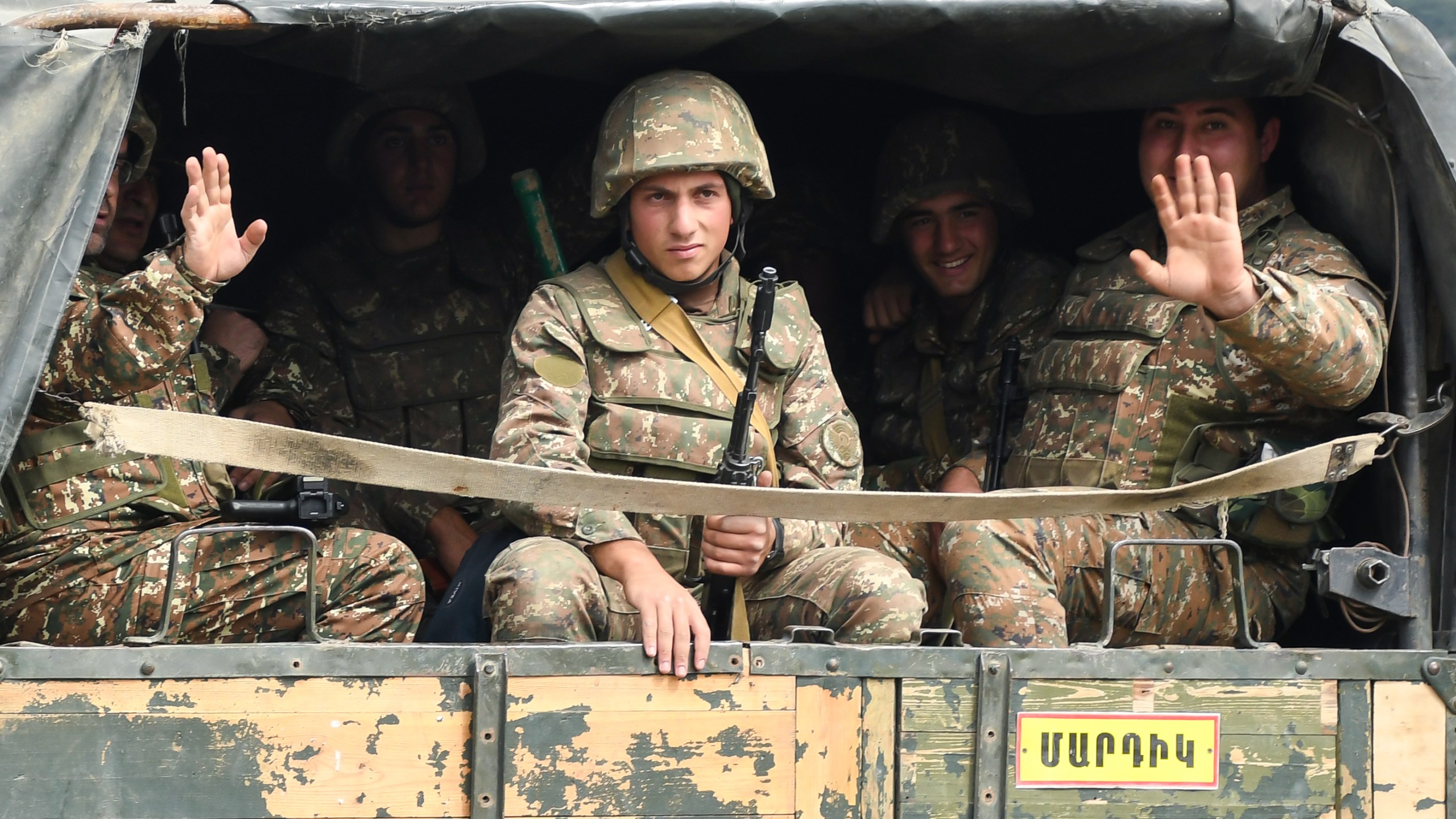 Servicemen of Karabakh's Defence Army wave while riding in the back of a truck on the way to the town of Martakert after Azerbaijani forced attacked the autonomous Nagorno Karabakh region on Sept. 29, 2020. (NAREK ALEKSANYAN/AFP via Getty Images)