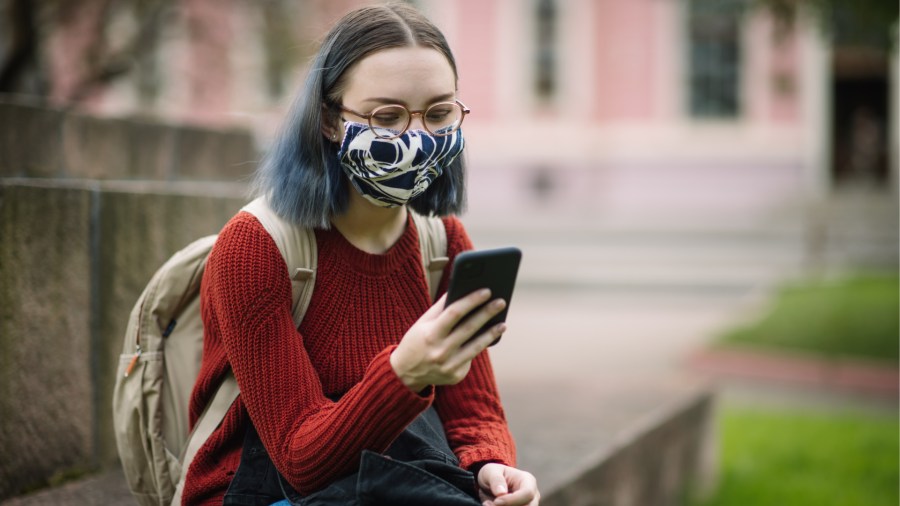 A student in a face mask checks her phone in this undated file photo. (Getty Images)