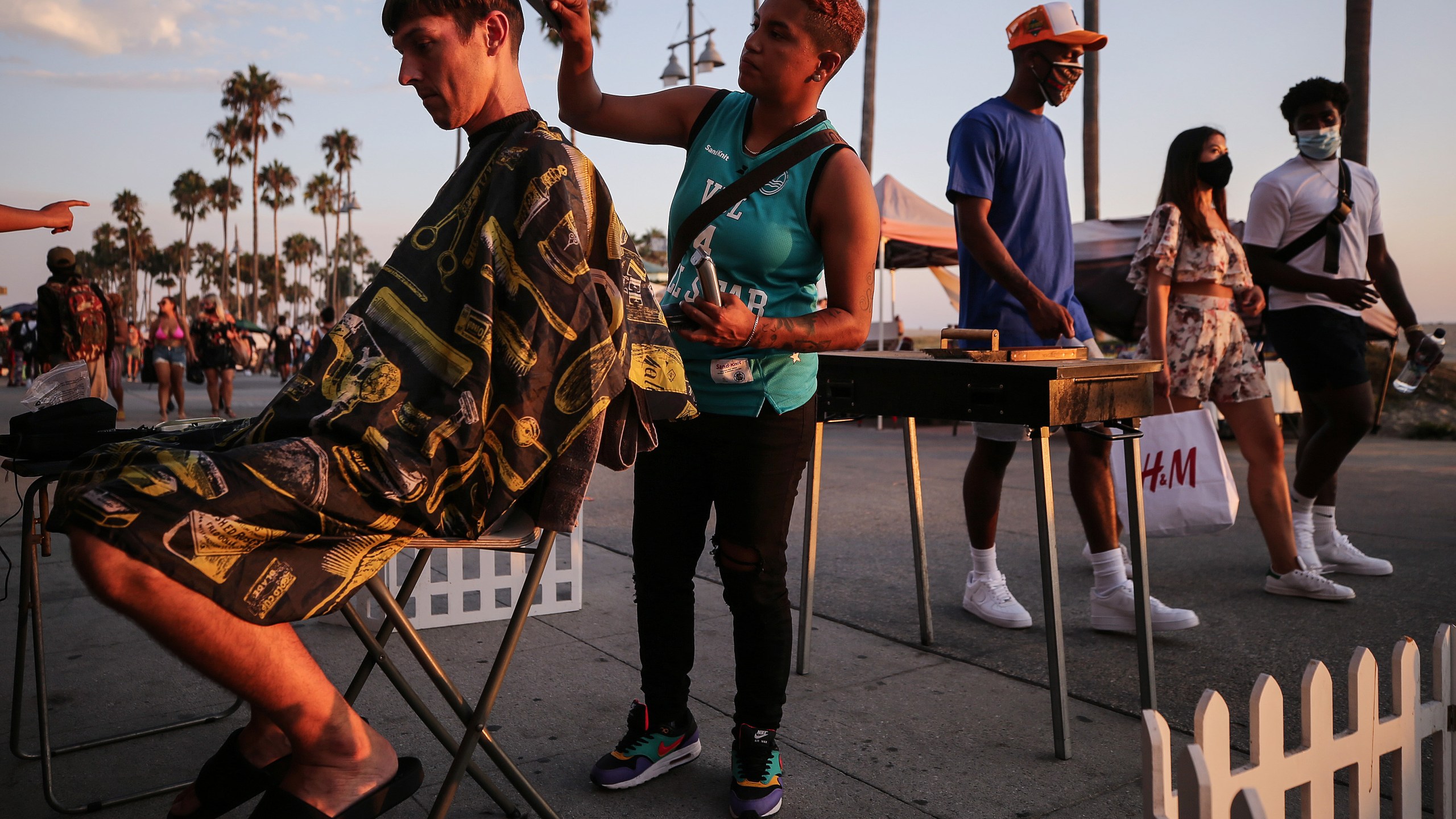 Joy Aguilar cuts Cooper Vanhoose's hair on the Venice Beach boardwalk on the first day of the Labor Day weekend amid a heatwave on Sept. 5, 2020 in Venice, Calif. Aguilar said she is offering haircuts outdoors along the beach as many hair salons remain closed due to the coronavirus pandemic. Temperatures soared across California that day. (Mario Tama/Getty Images)