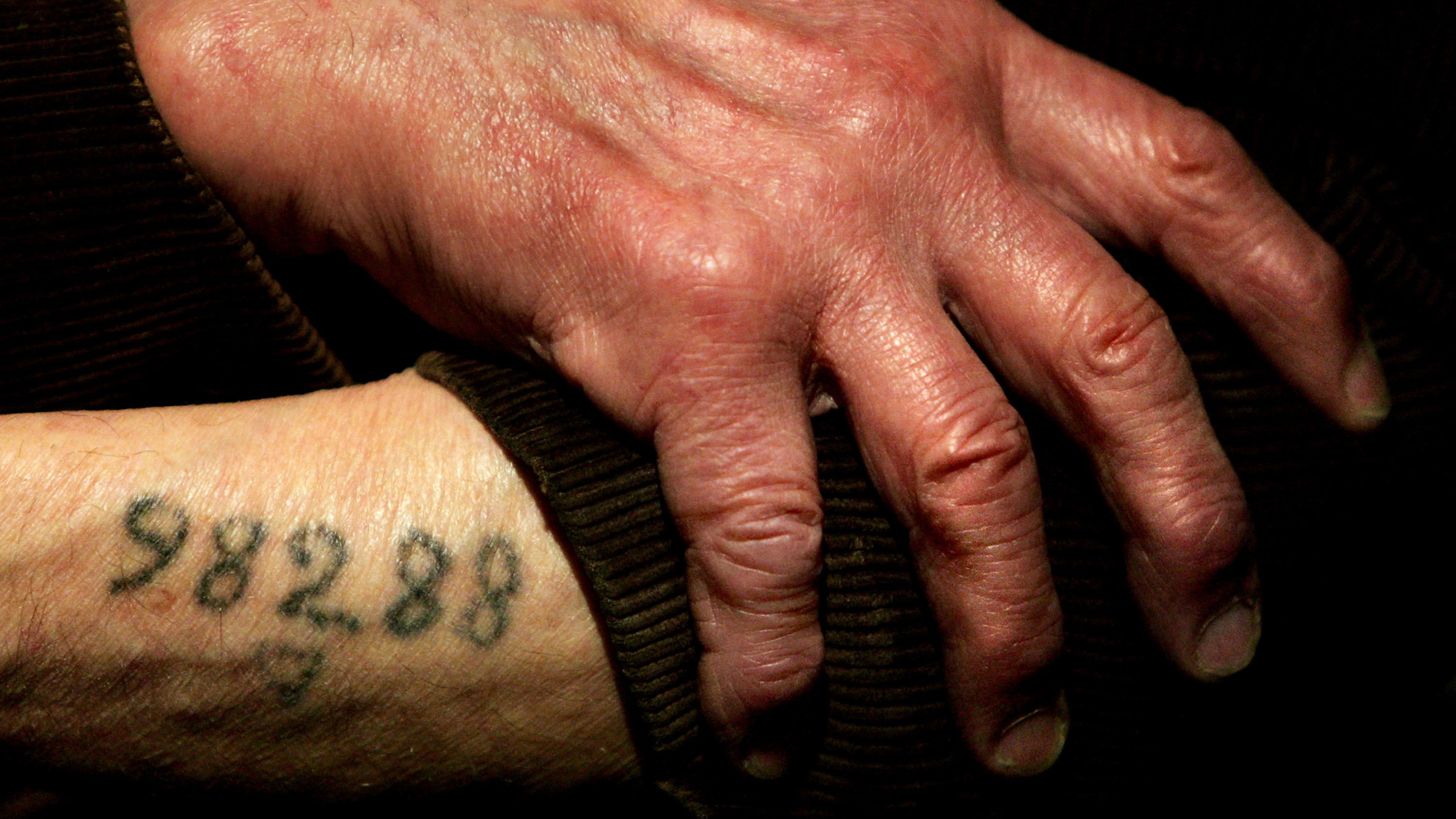 Auschwitz survivor Leon Greenman, prison number 98288, displays his number tattoo on Dec. 9, 2004, at the Jewish Museum in London. (Ian Waldie / Getty Images)