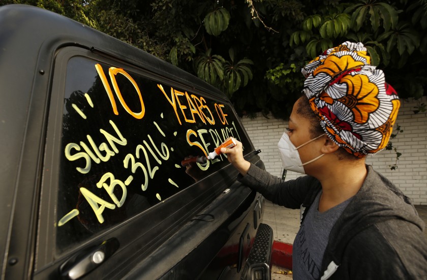 Courtney Banks who has worked in events and catering at the Chateau Marmont writes message on windows of vehicles in support of workers who lost their jobs at the hotel in this undated photo. (Al Seib/Los Angeles Times)