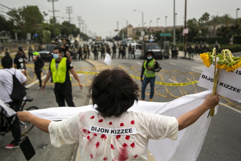 Brenda Baraquil stands in front of L.A. County sheriff’s deputies wearing riot gear during a Sept. 12 protest in South L.A. calling for justice in the aftermath of the killing of Dijon Kizzee. (Josie Norris / Los Angeles Times)