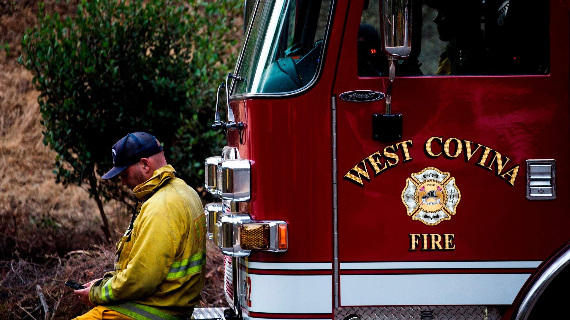 West Covina firefighters rest on their fire truck as the Bobcat Fire burns in the San Gabriel mountains above Monrovia on September 16, 2020. (RINGO CHIU/AFP via Getty Images)