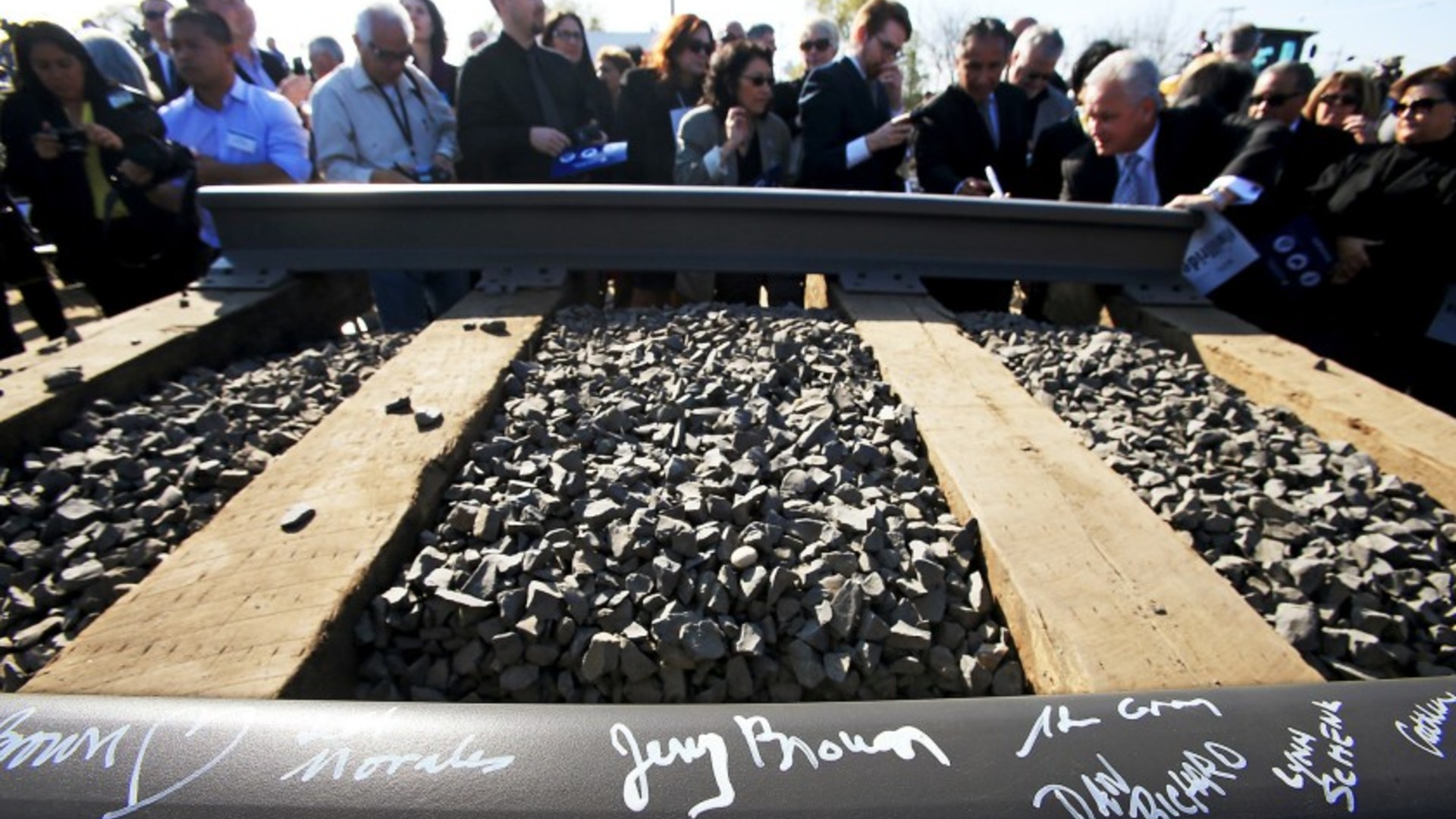 Guests, including then Gov. Jerry Brown, sign a rail segment during a groundbreaking ceremony for a California bullet train station in Fresno on Jan. 6, 2015.(Los Angeles Times)