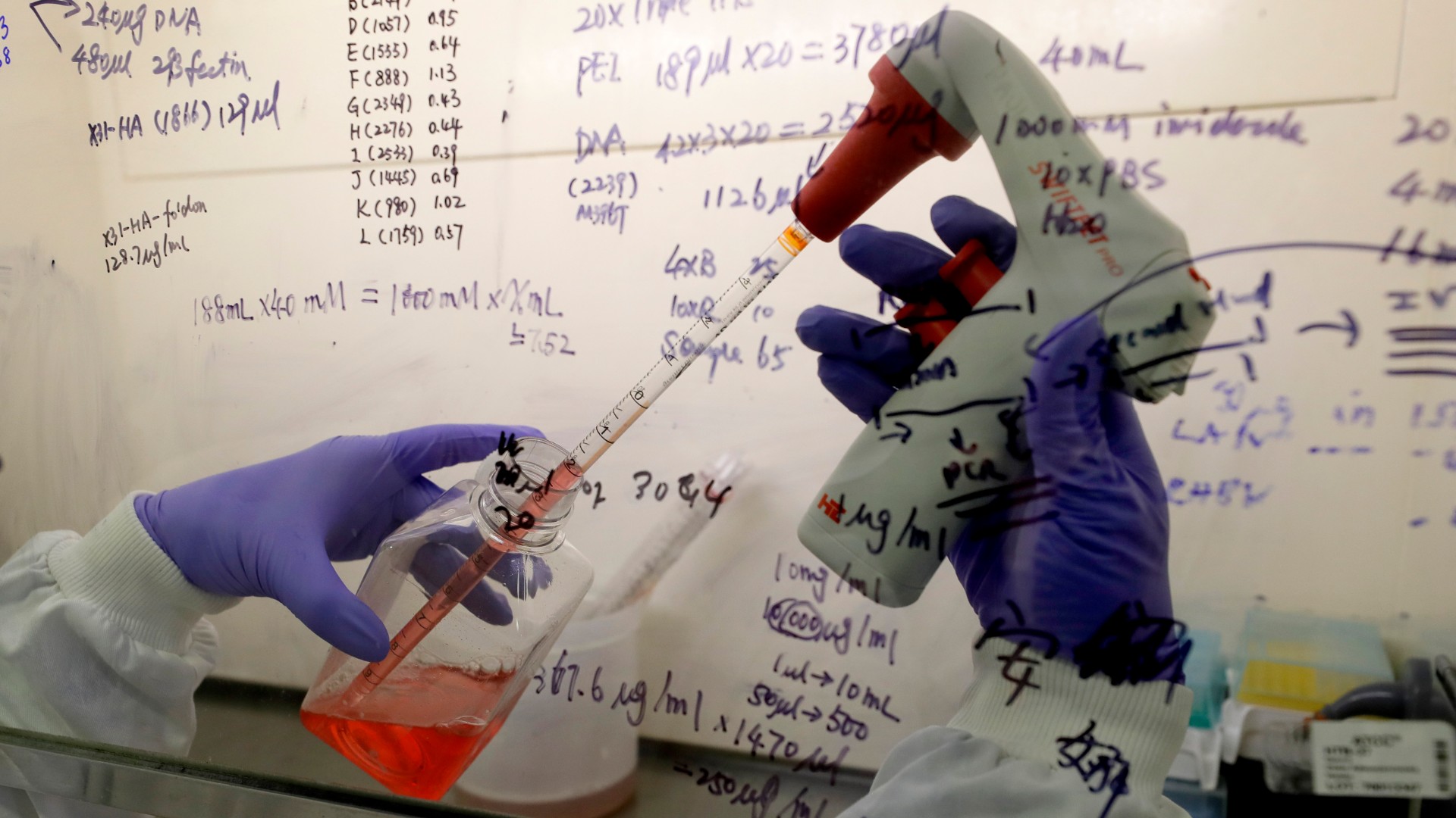 In this July 30, 2020 photo, Kai Hu, a research associate transfers medium to cells, in the laboratory at Imperial College in London. (AP Photo/Kirsty Wigglesworth)