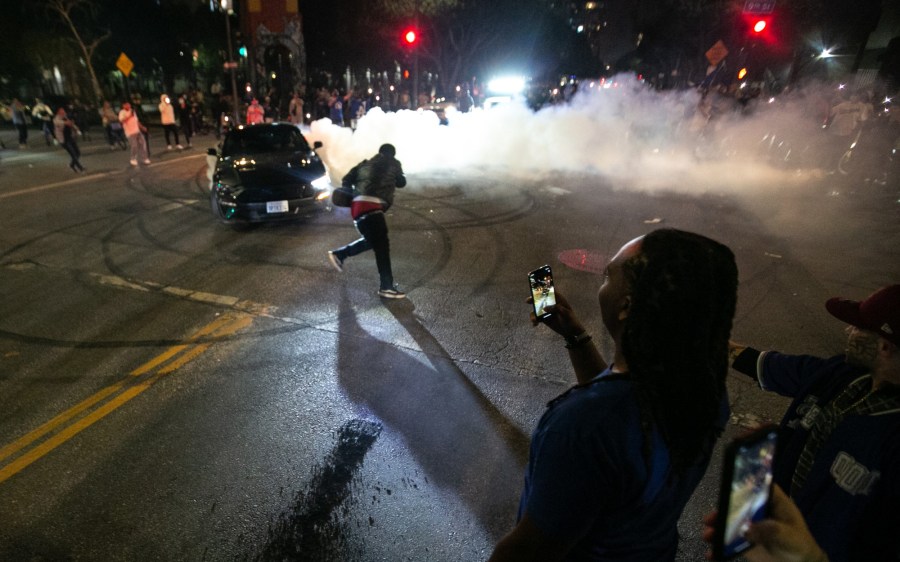 Fans watch a car do burnouts in downtown Los Angeles following the Los Angeles Dodgers World Series win over the Tampa Bay Rays on Oct. 27, 2020. (Jason Armond / Los Angeles Times)