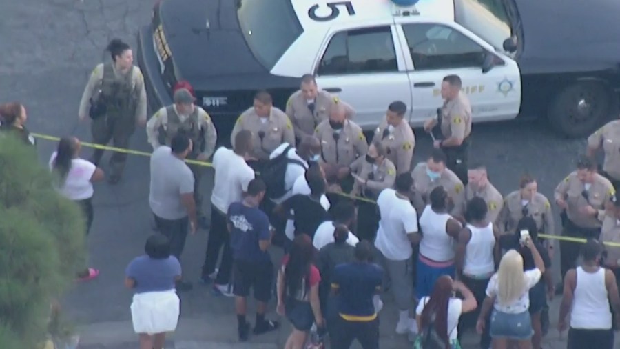 Bystanders and law enforcement exchange words at the scene where deputies shot and killed a man in Willowbrook on Oct. 16, 2020. (KTLA)