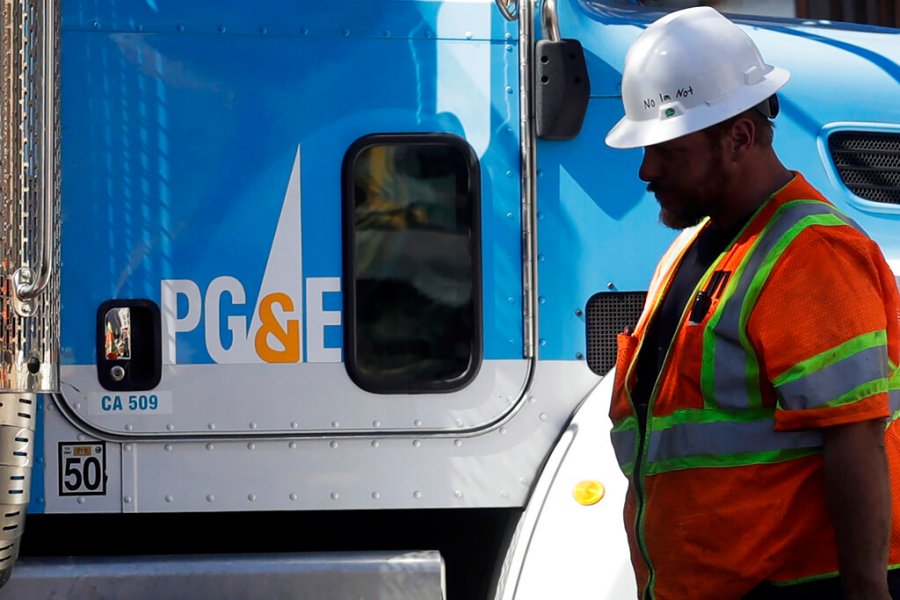 In this Aug. 15, 2019 file photo, a Pacific Gas and Electric worker walks in front of a truck in San Francisco. (AP Photo/Jeff Chiu,File)